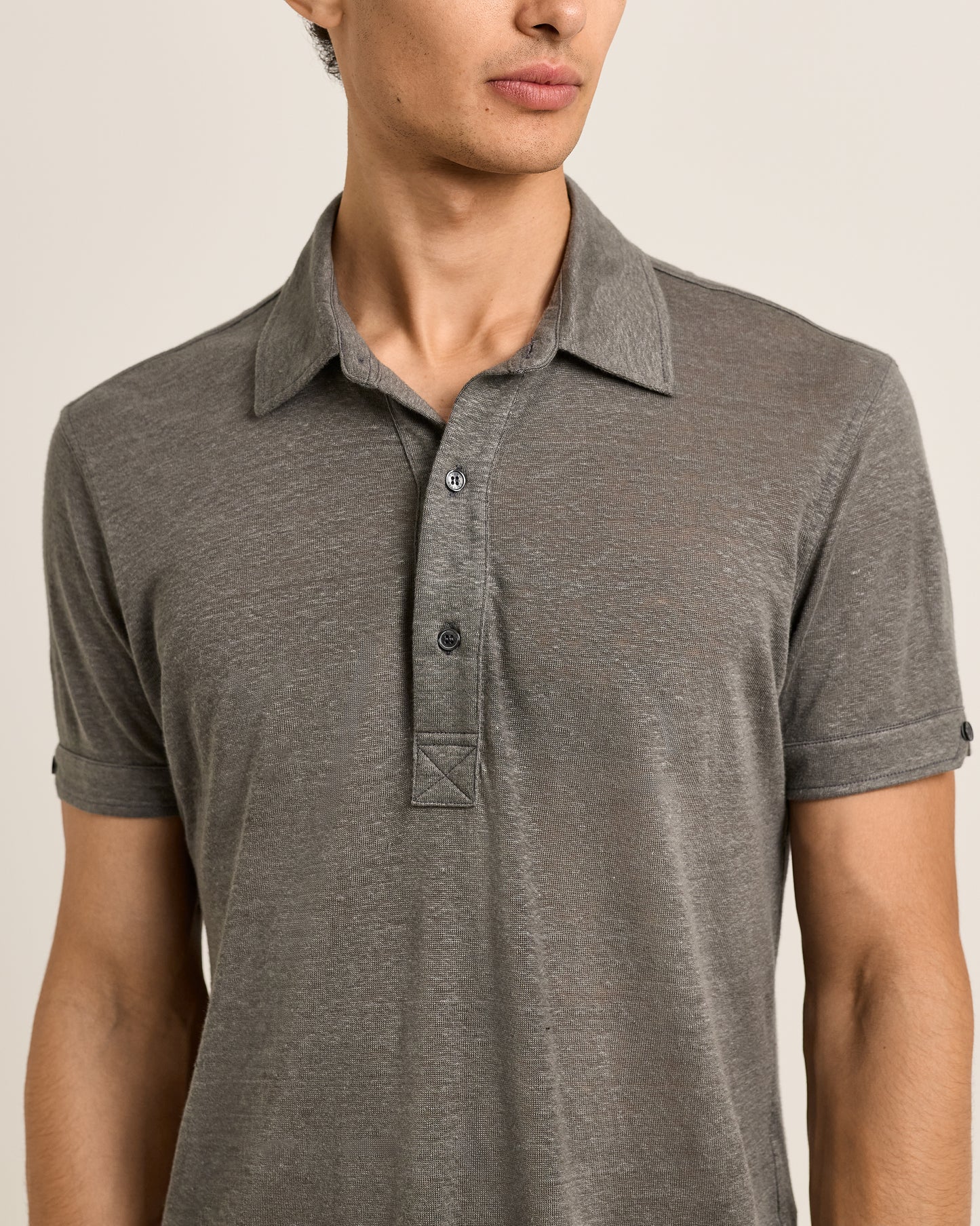 Man wearing a gray polo shirt against a neutral background