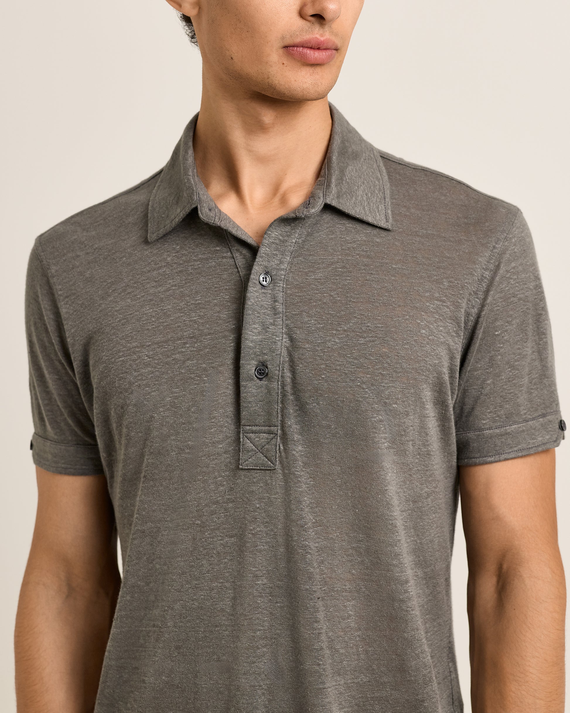 Man wearing a gray polo shirt against a neutral background