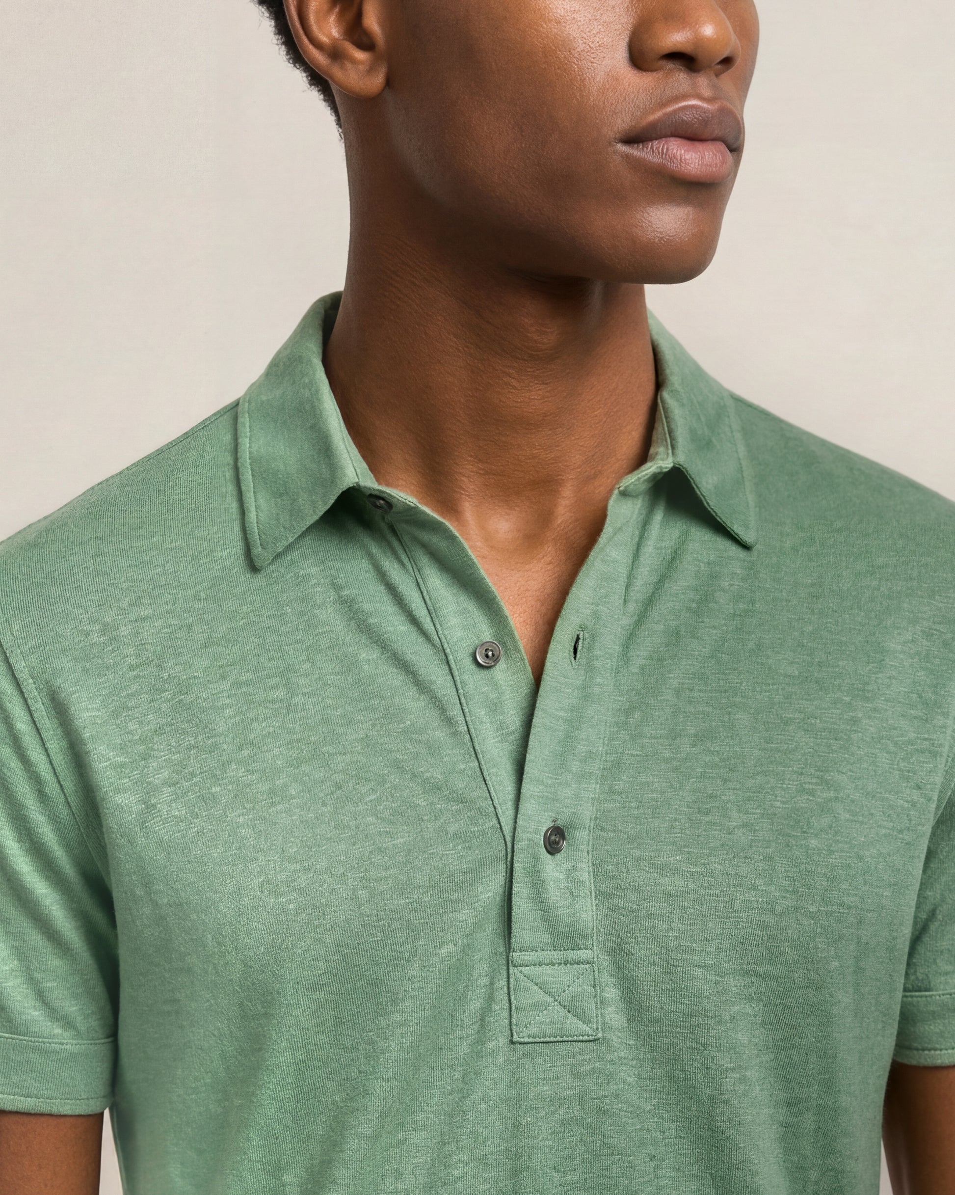 Man wearing a green polo shirt against a neutral background