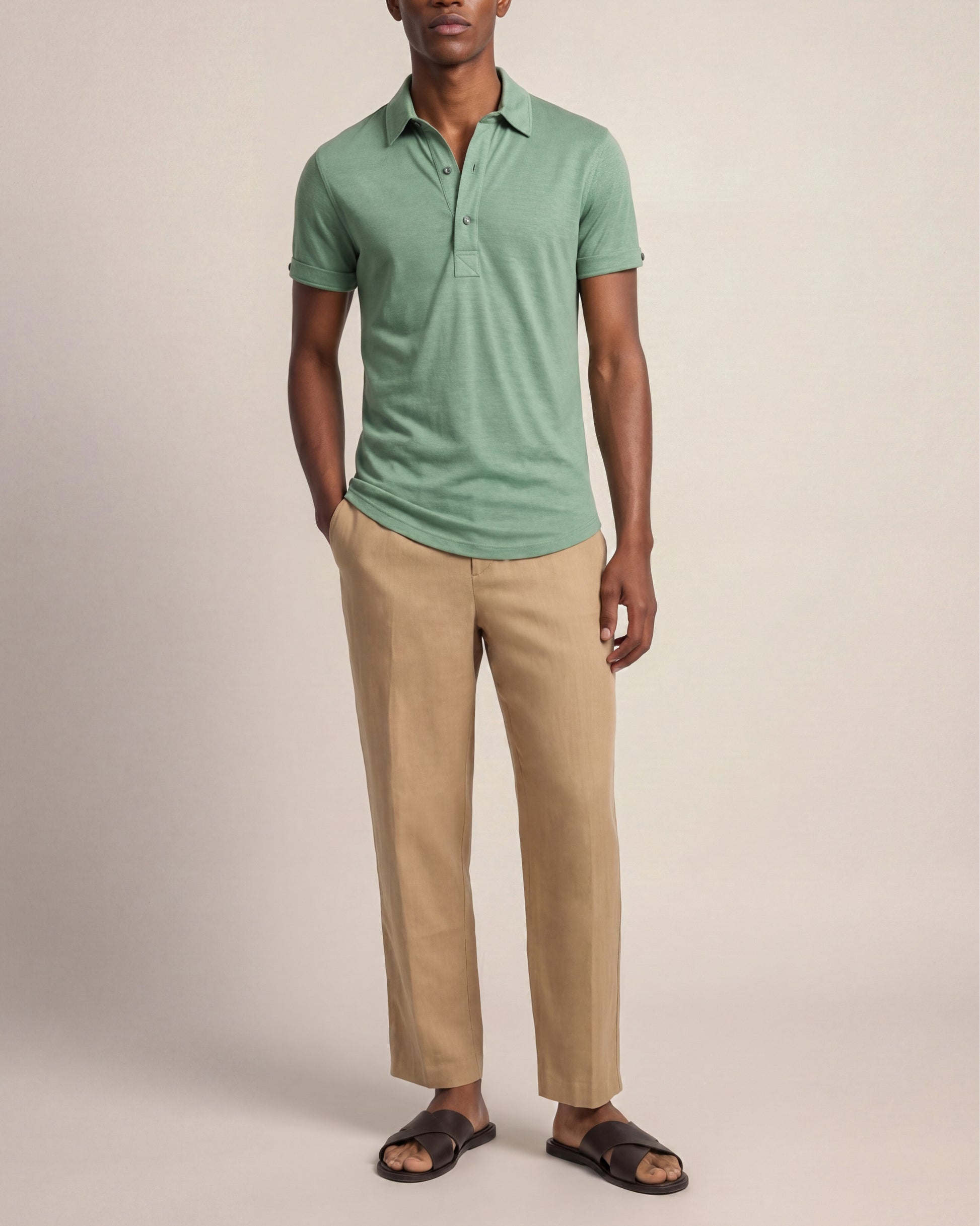 Man wearing a green polo shirt and beige pants against a plain background