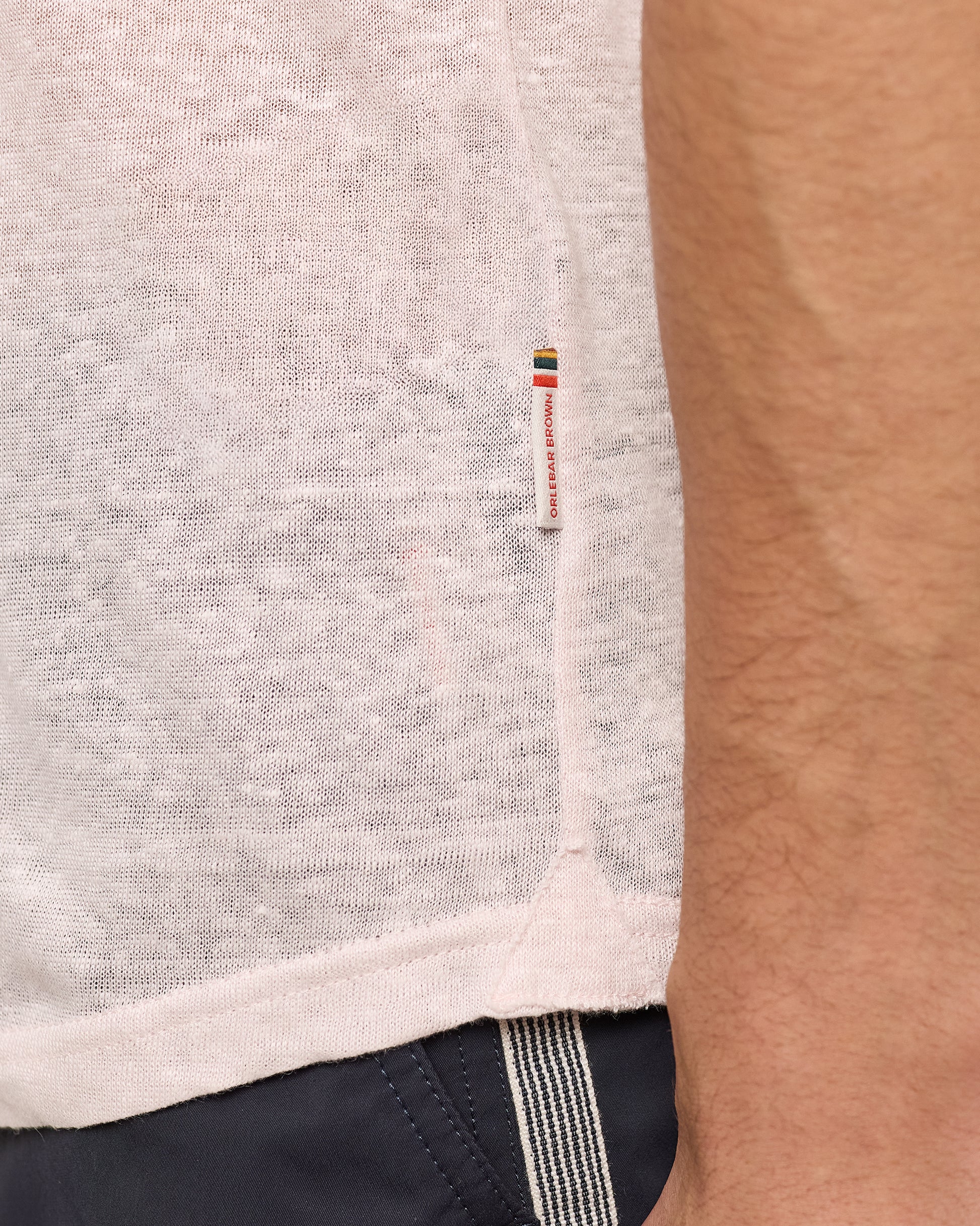 Close-up of a pink garment with a brand logo on a person wearing it.