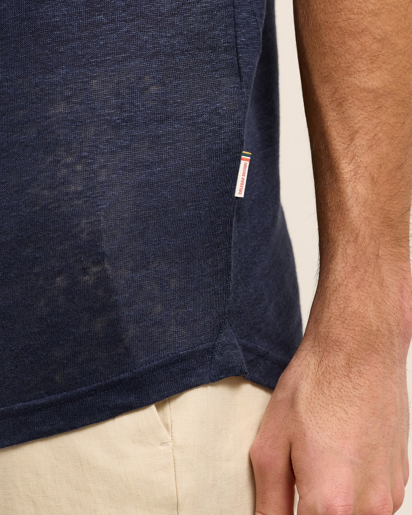 Closeup of navy linen polo shirt with Orlebar Brown logo tag on seam