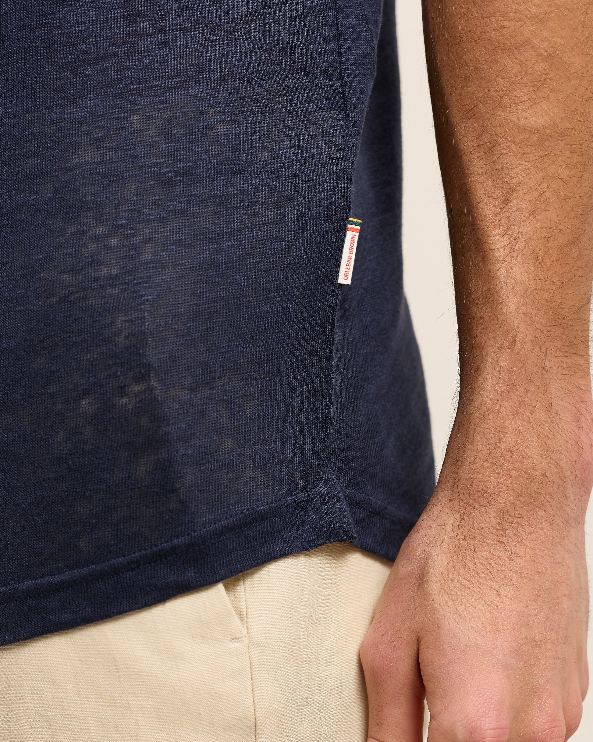 Closeup of navy linen polo shirt with Orlebar Brown logo tag on seam