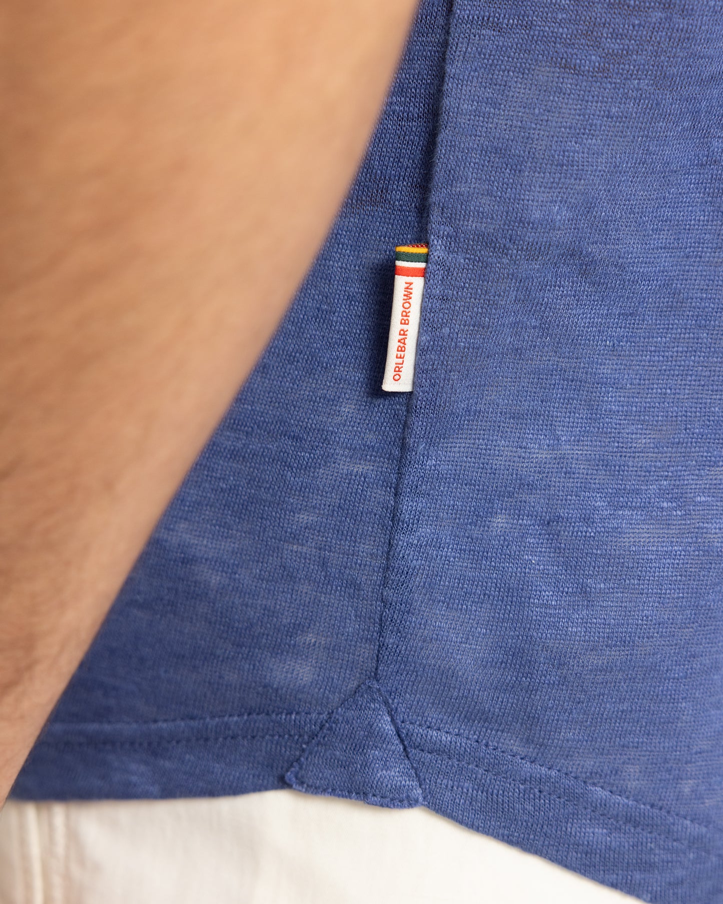Close-up of a blue garment with a brand label on a beige background