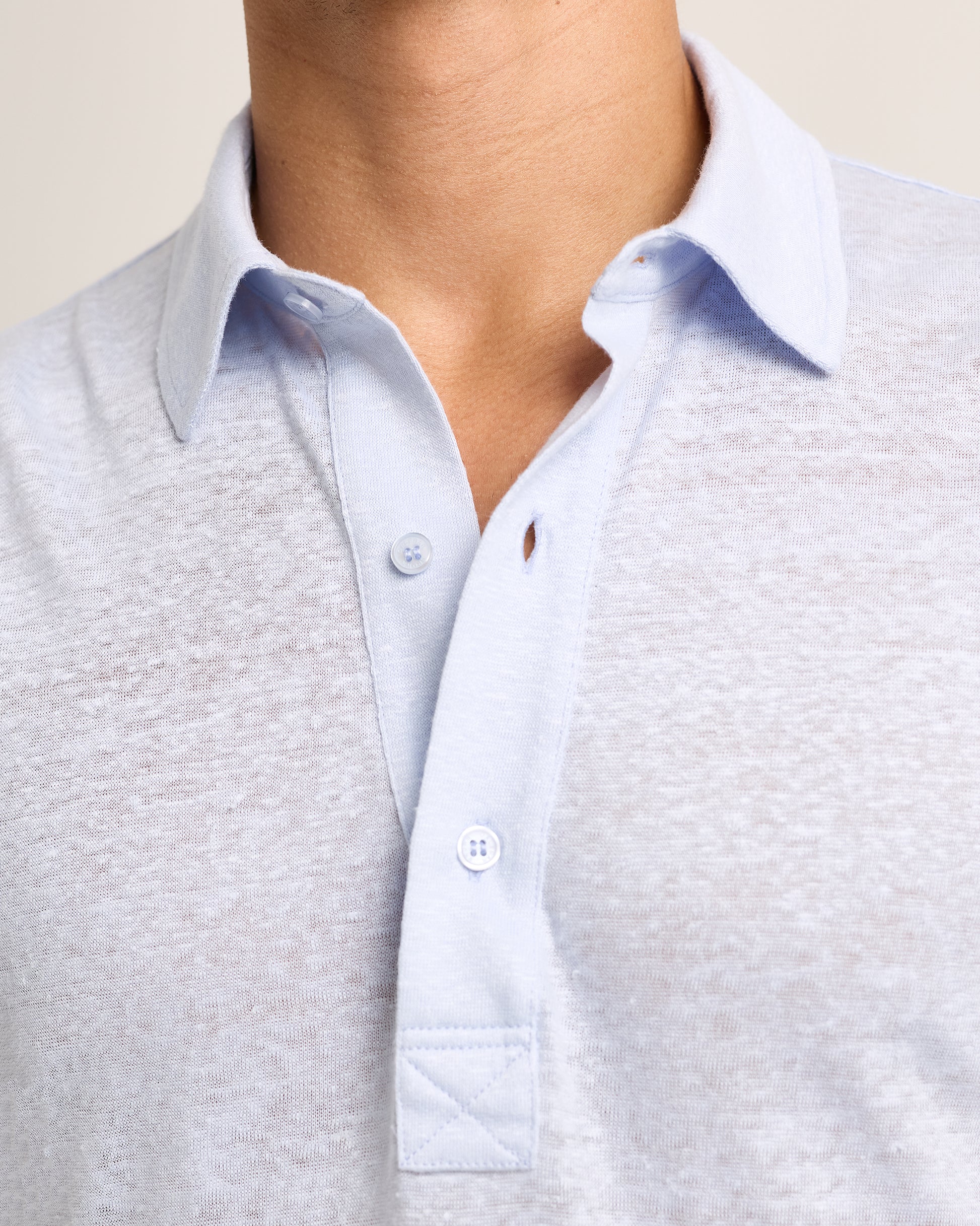 Close-up of a person wearing a light blue textured polo 
