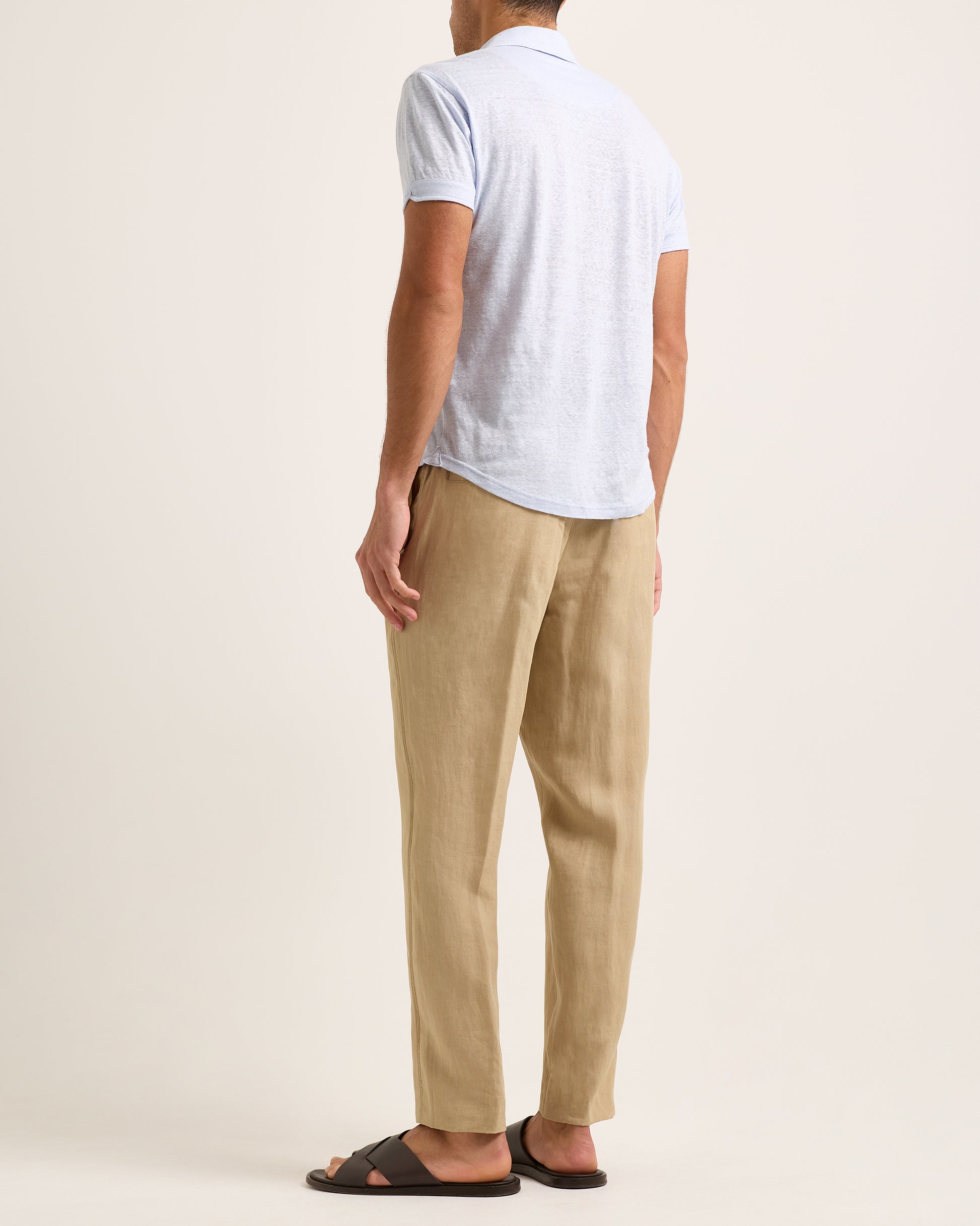 Model wearing light blue polo shirt with beige trousers on a white background