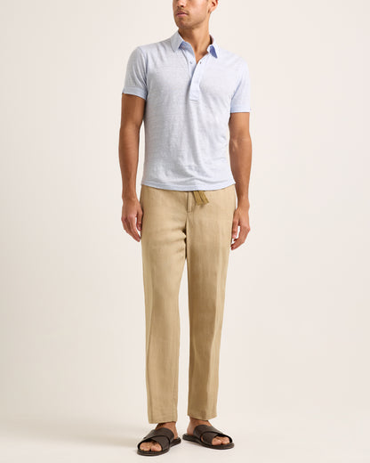 Model wearing light blue polo shirt with beige trousers on a white background
