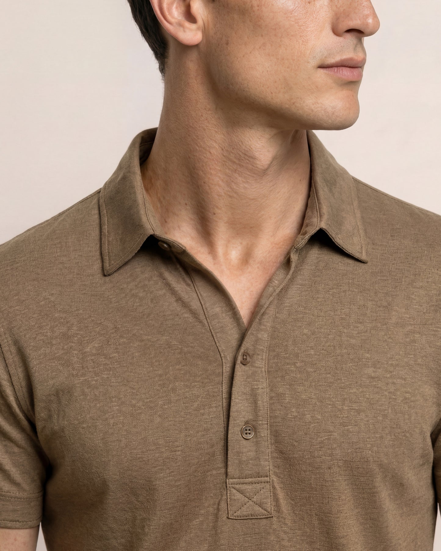 Man wearing a brown polo shirt against a beige background