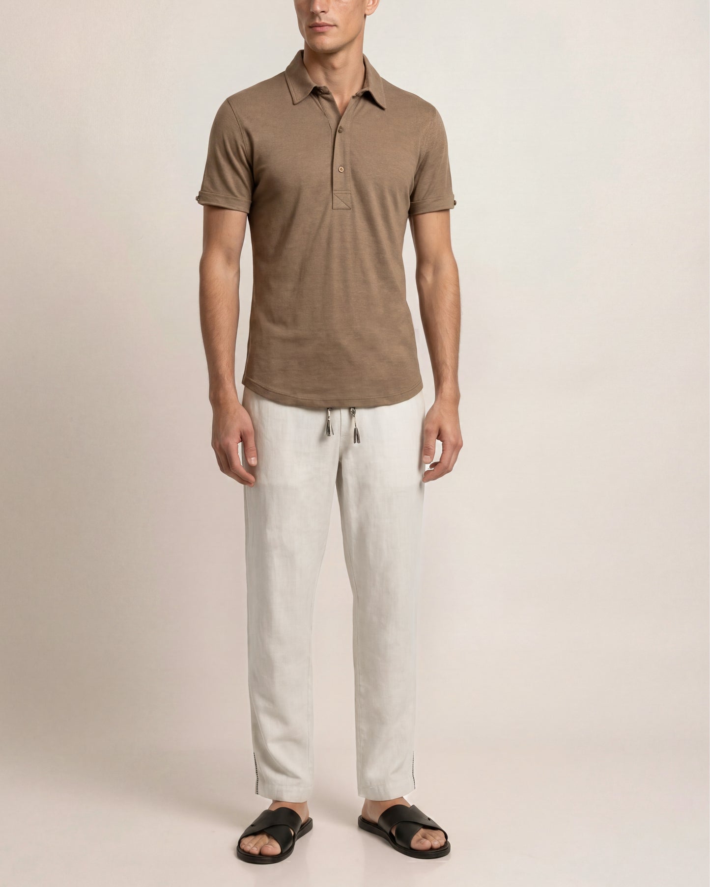 Man wearing a brown polo shirt and light-colored pants on a plain background