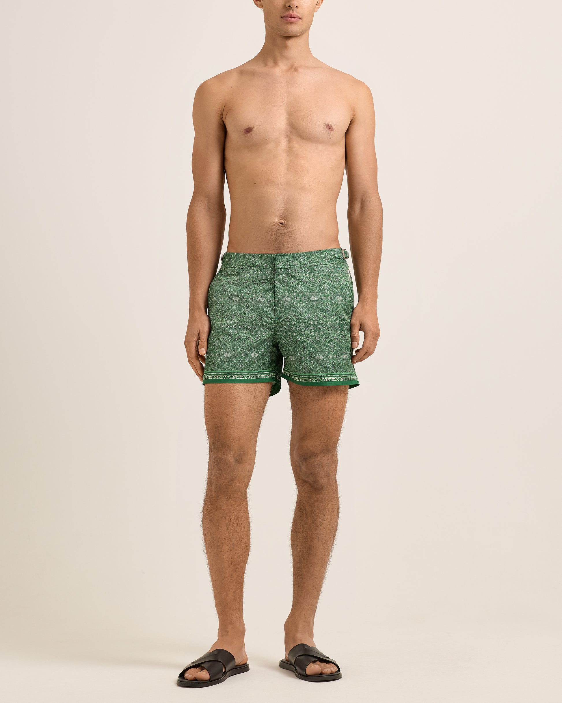 Man wearing green patterned shorts on a beige background