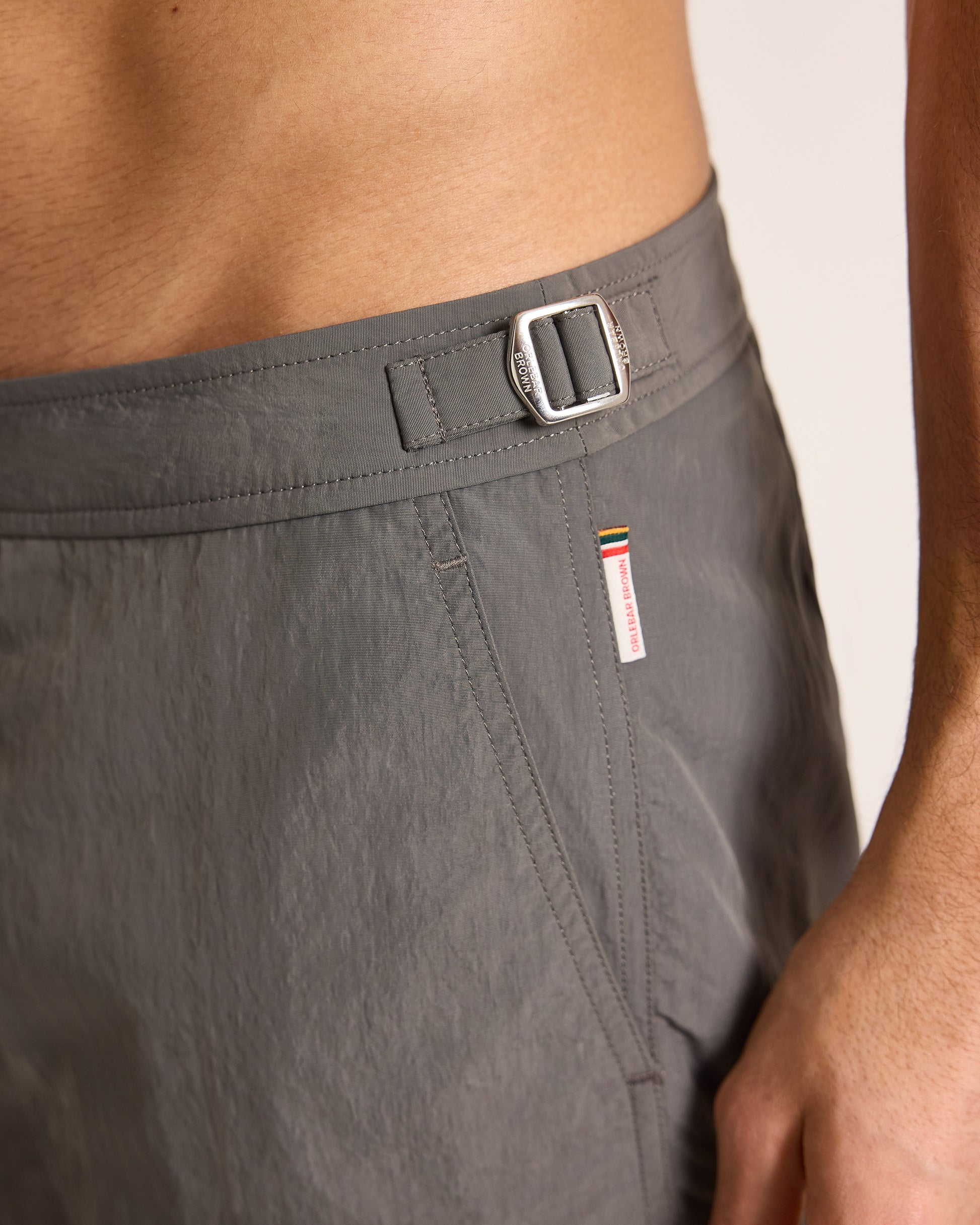 Gray shorts with a side adjuster and brand tag on a neutral background