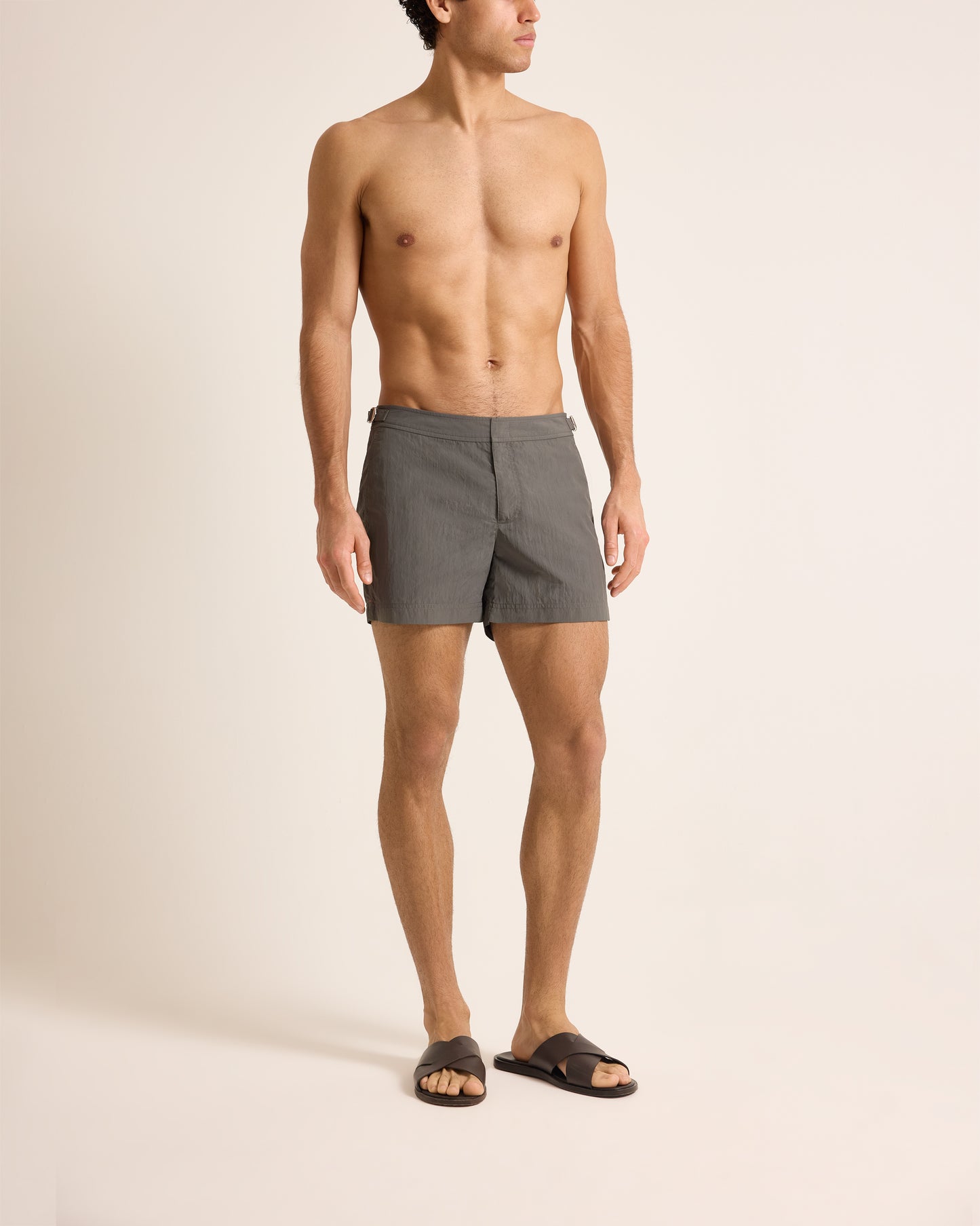 Man wearing gray swim shorts on a beige background