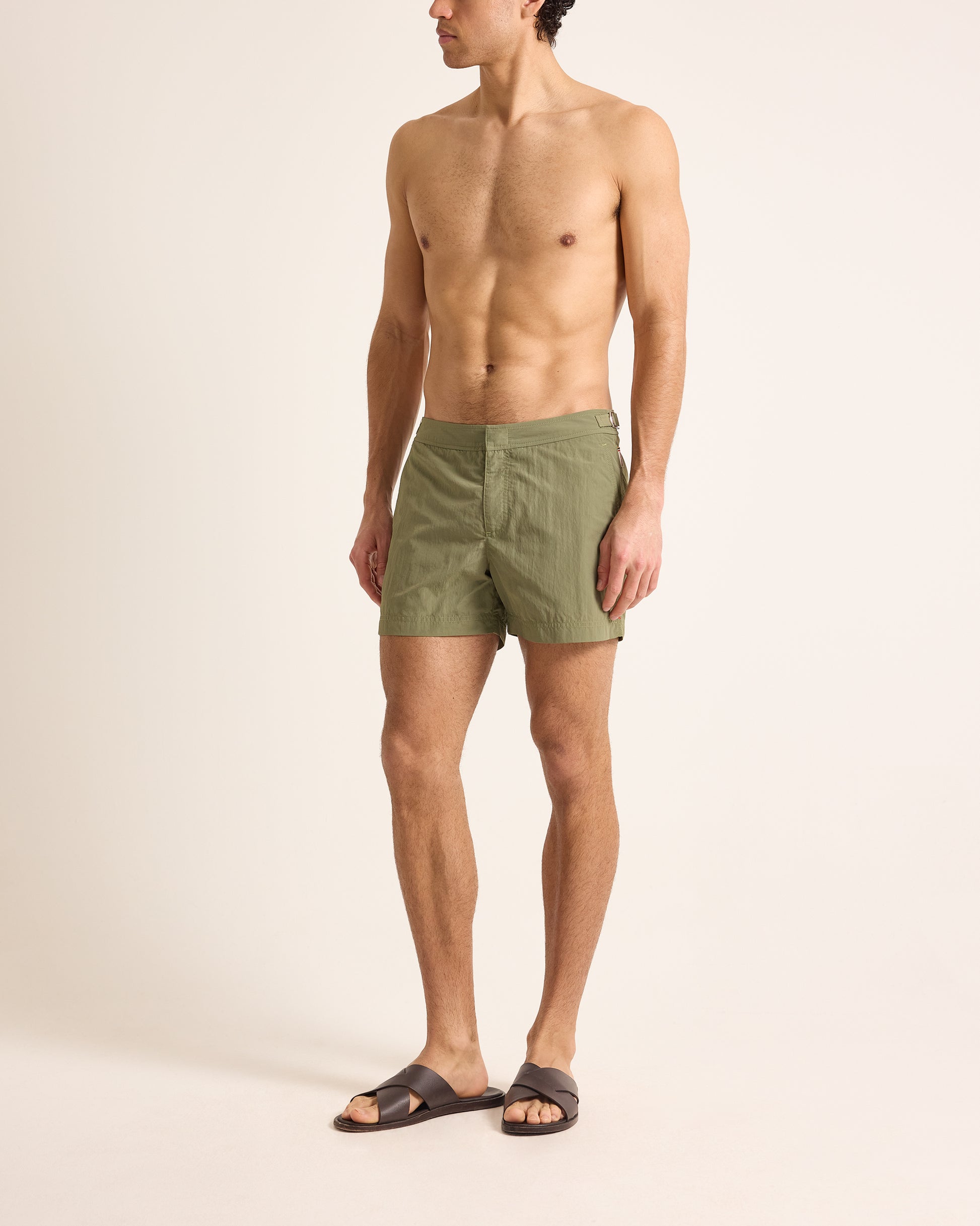 Man wearing green swim shorts on a beige background