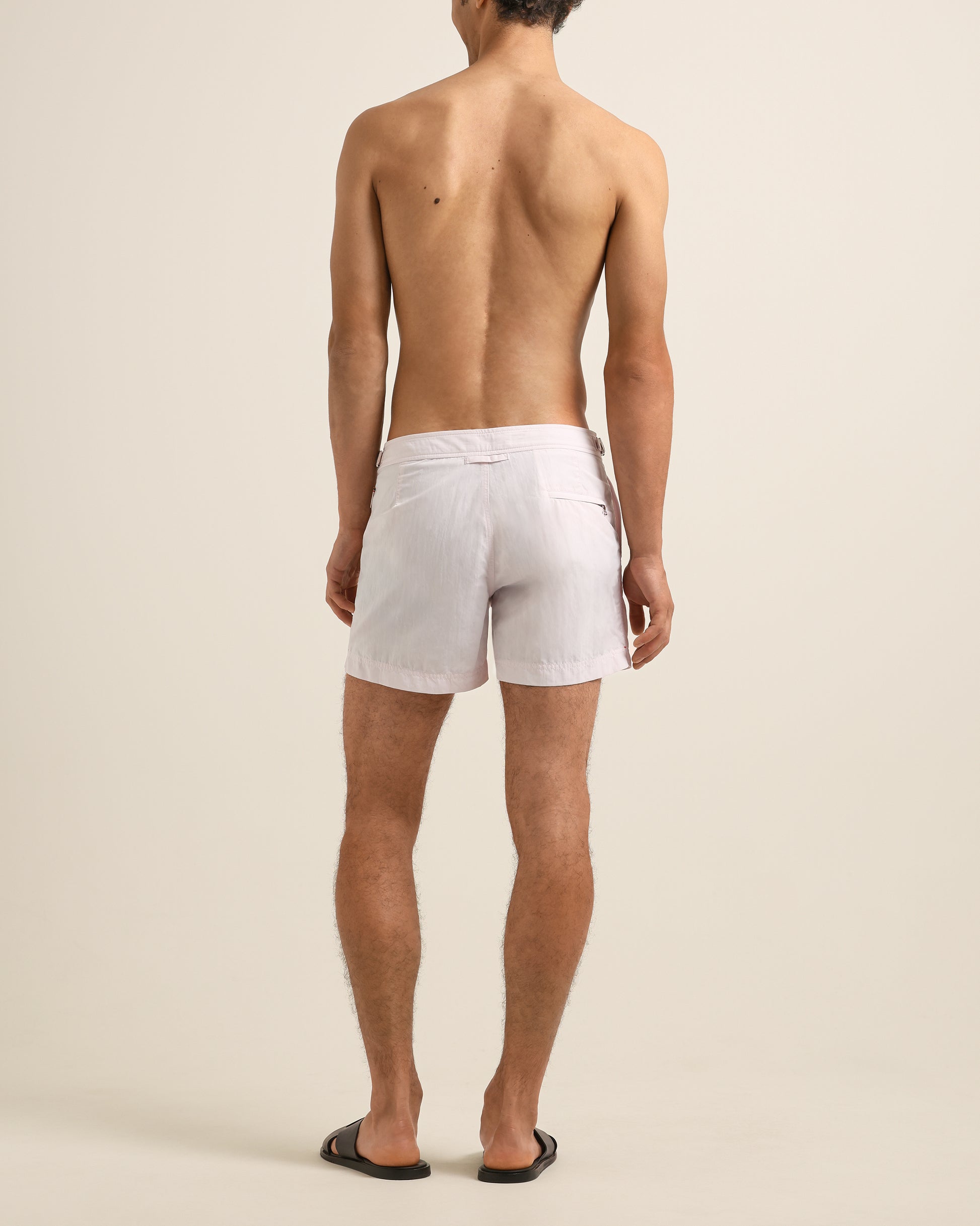Man wearing white swim shorts on a beige background