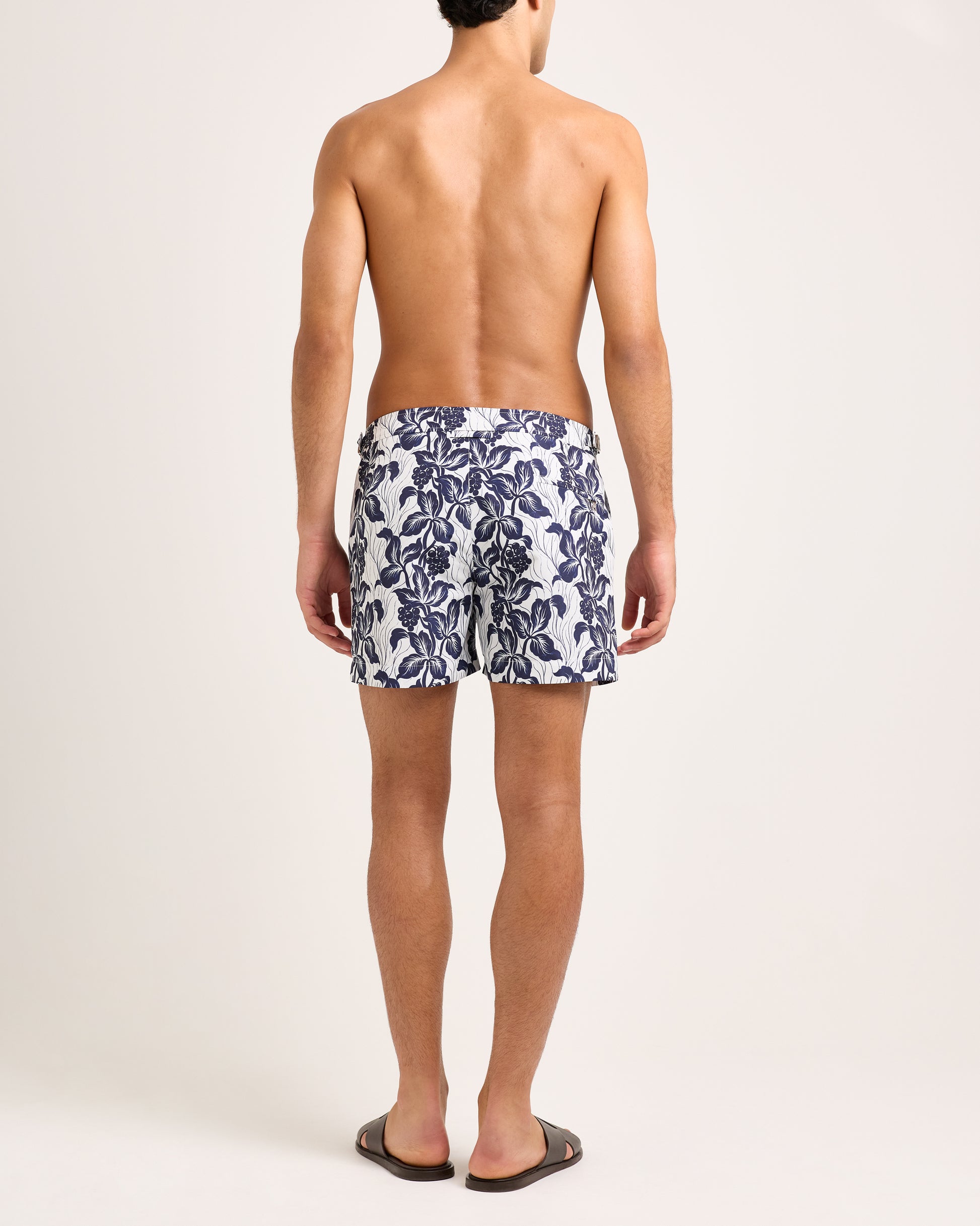 Model wearing floral navy swim shorts on a white background