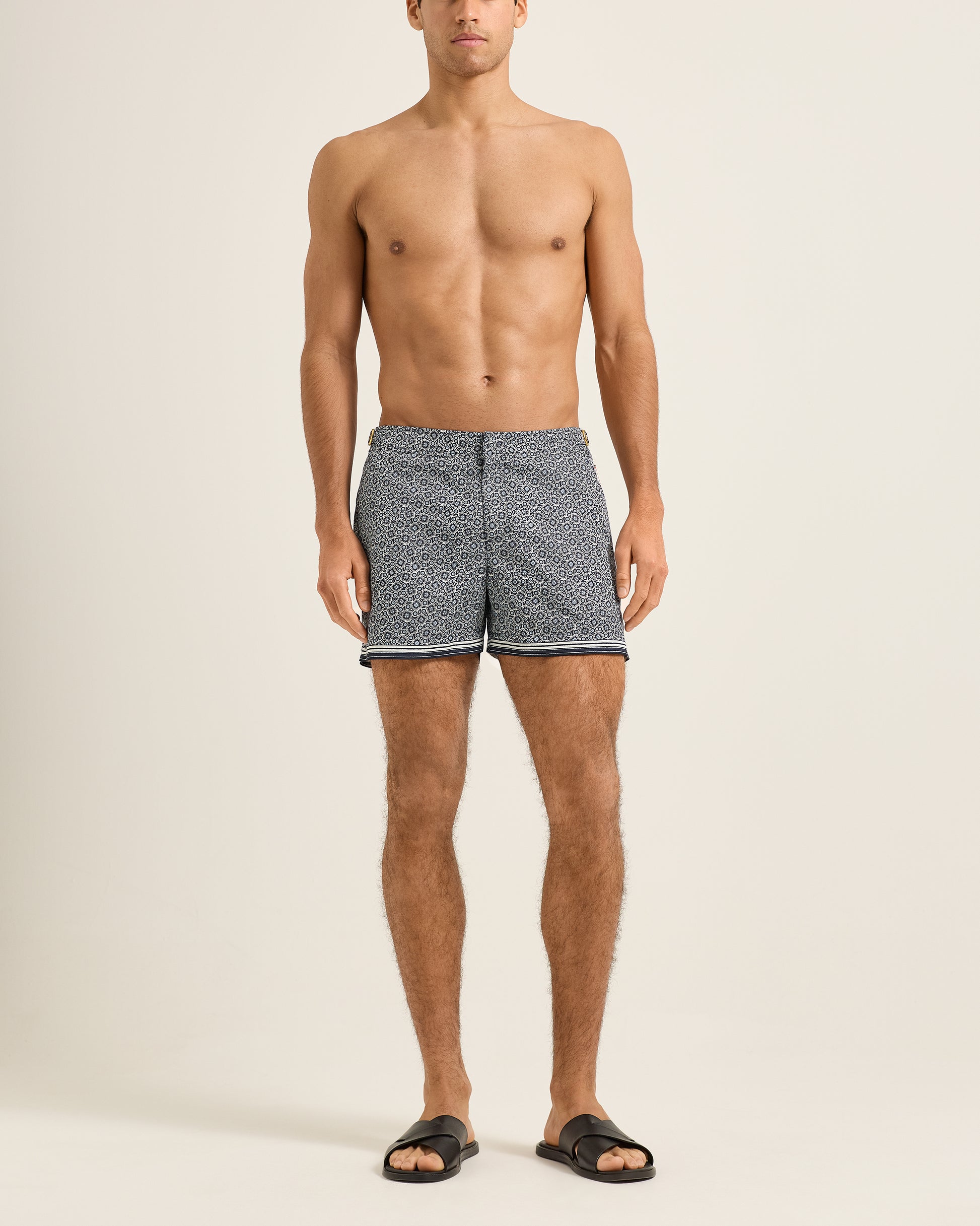 Man wearing patterned swim shorts on a plain background