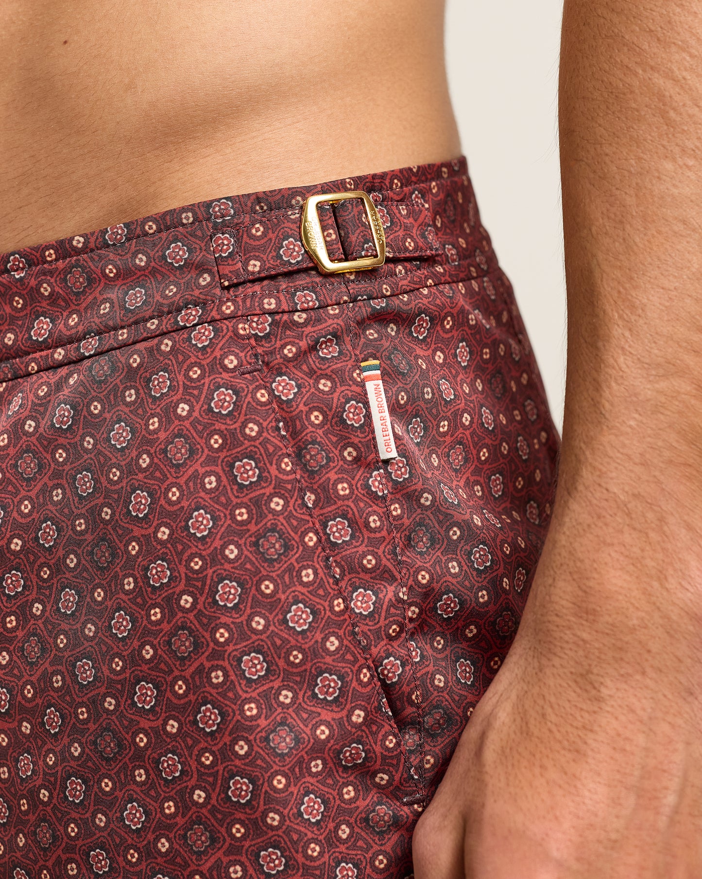 Maroon patterned shorts with a gold buckle and visible brand tag.