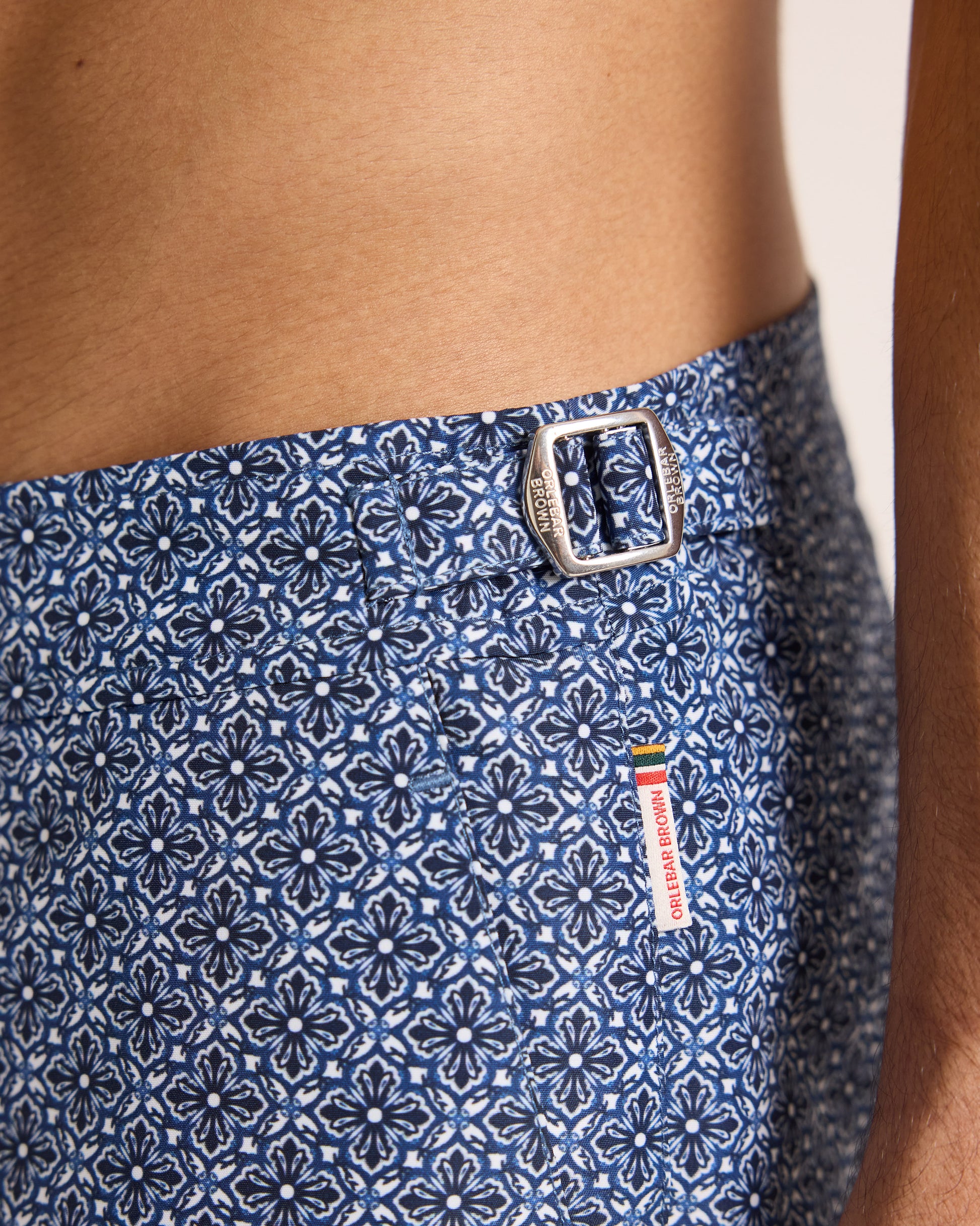 Man wearing blue patterned swim shorts on a beige background