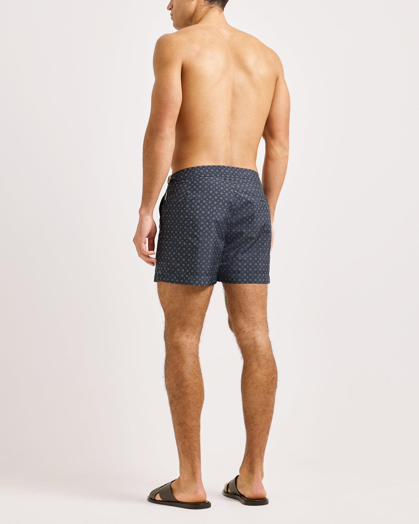 Man wearing navy patterned swim shorts on a white background