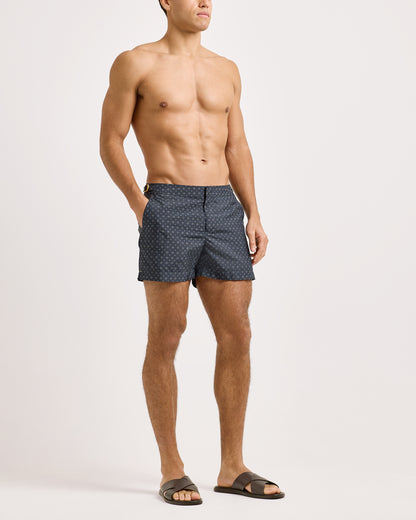 Man wearing navy patterned swim shorts on a white background