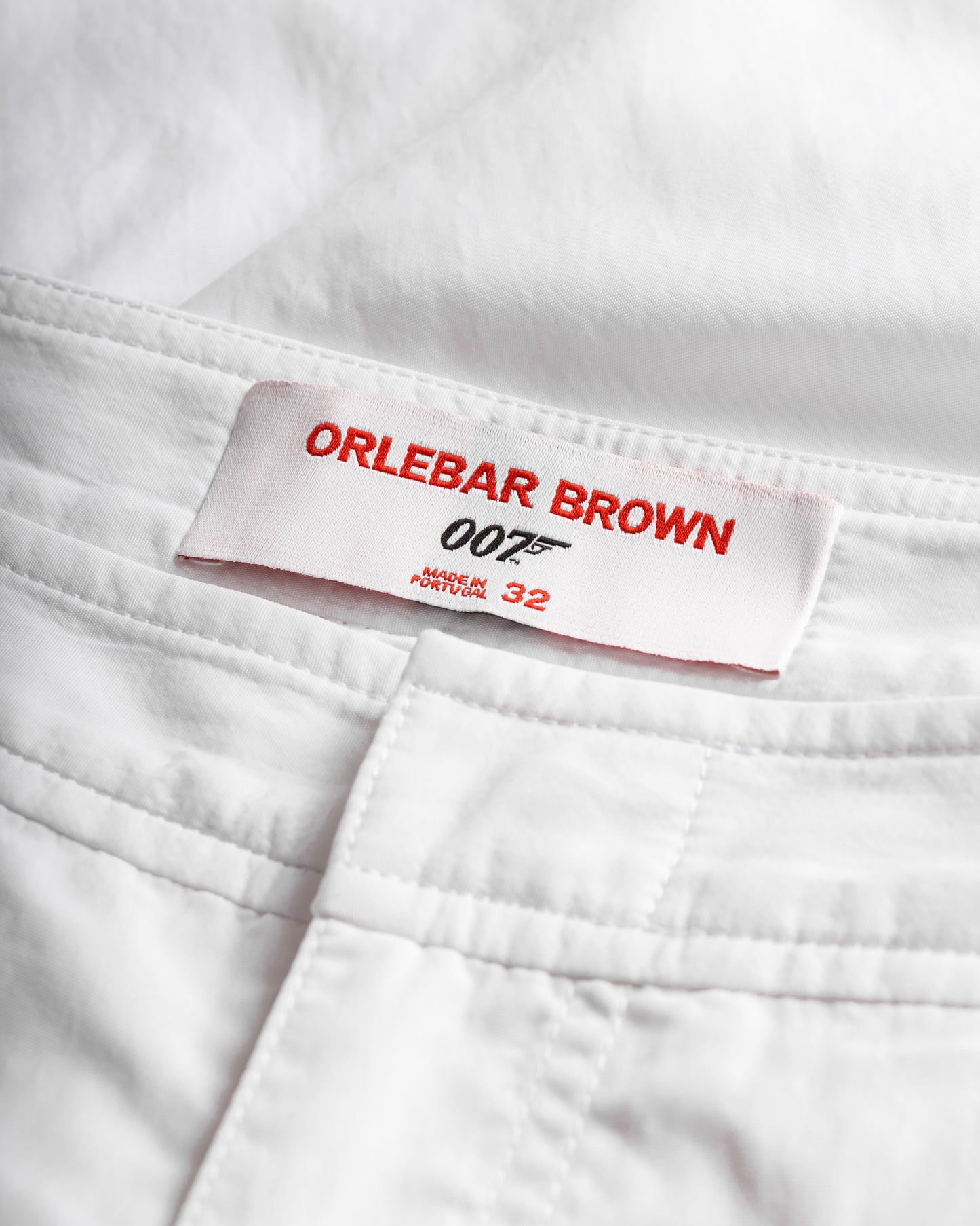 Close-up of a white garment with an Orlebar Brown label featuring James Bond branding.