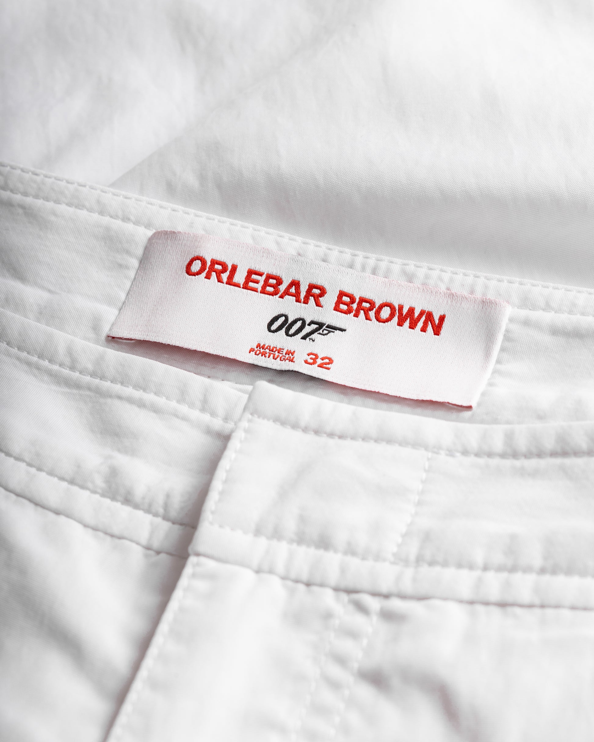 Close-up of a white garment with an Orlebar Brown label featuring James Bond branding.