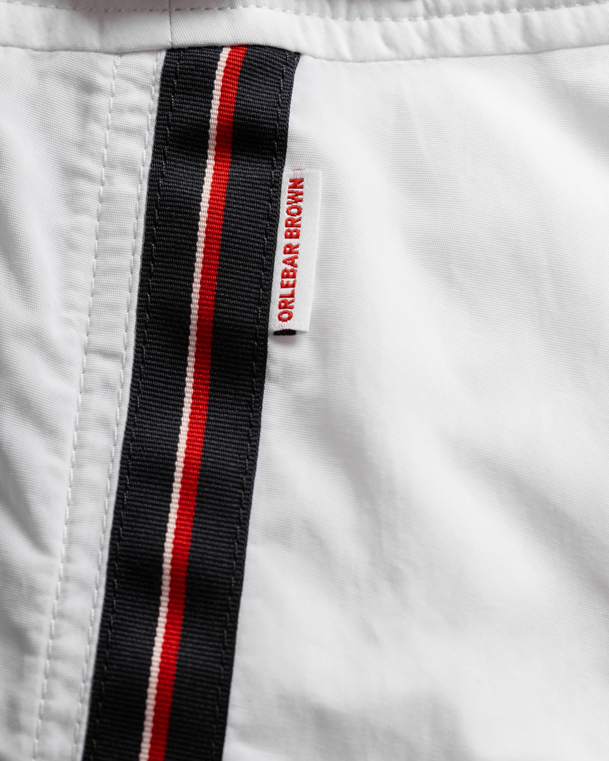 Close-up of a white jacket with a black and red striped band featuring text on a white background.