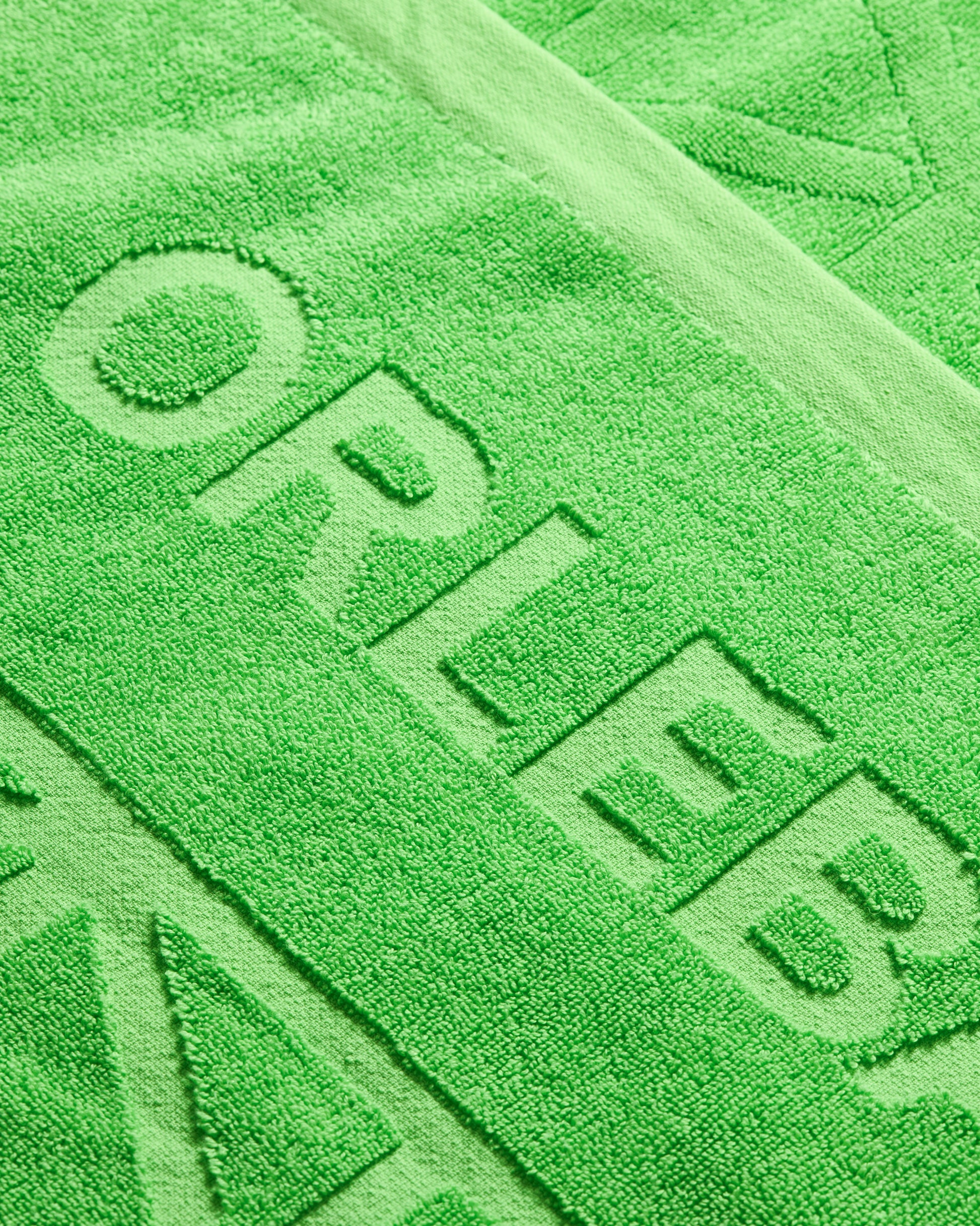 Close-up of a green towel with 'ORLEB' branding.