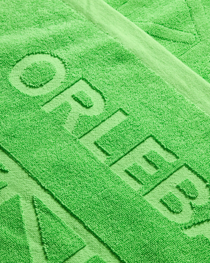 Close-up of a green towel with 'ORLEB' branding.