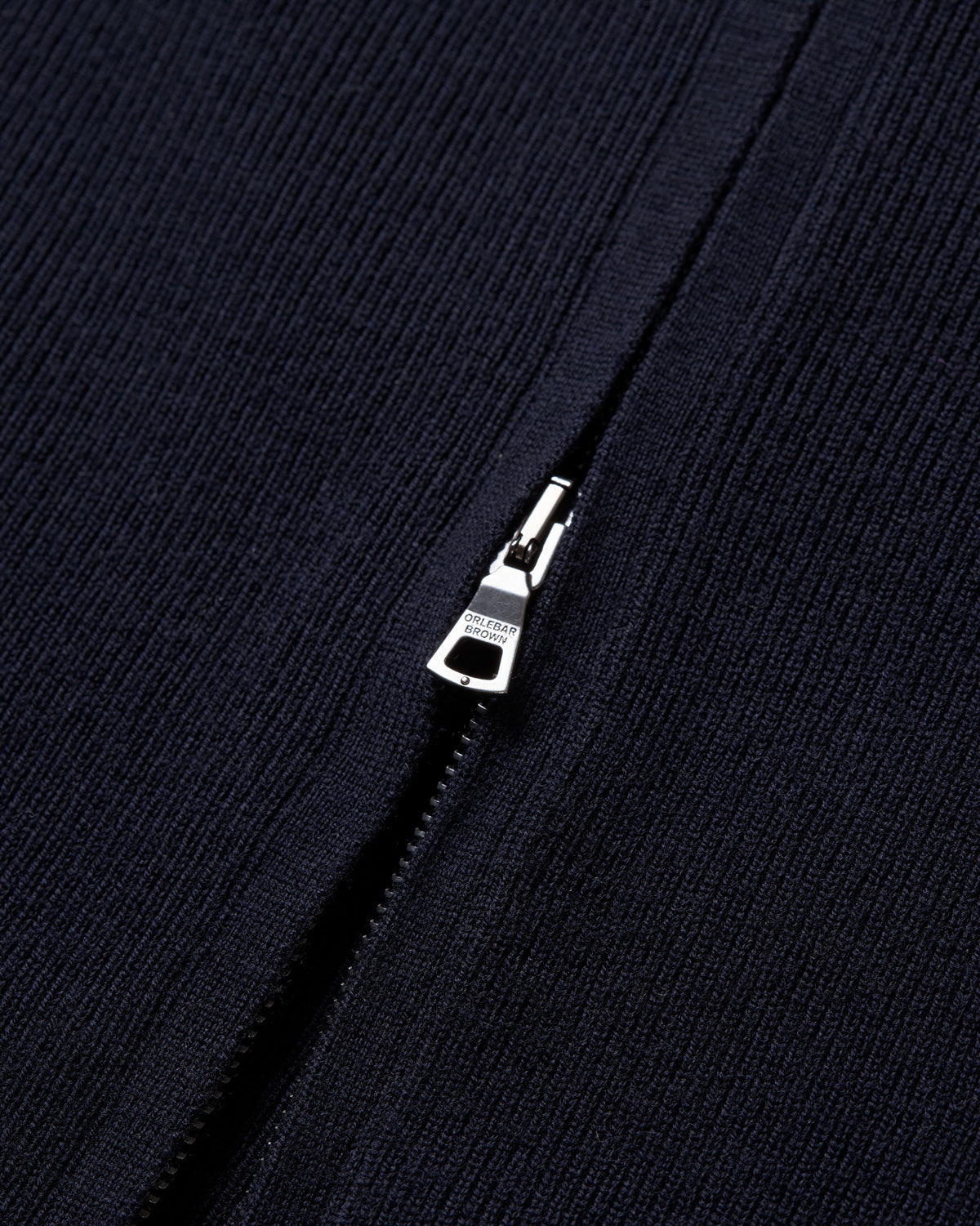 Close-up of a dark navy ribbed knit fabric with a silver metal zipper pull.