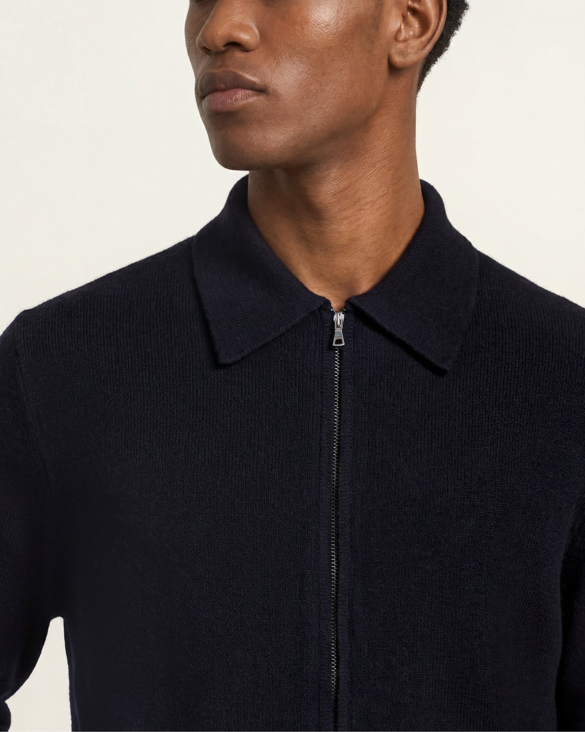 Close up of zipper and collar of the navy knitted zip up sweater
