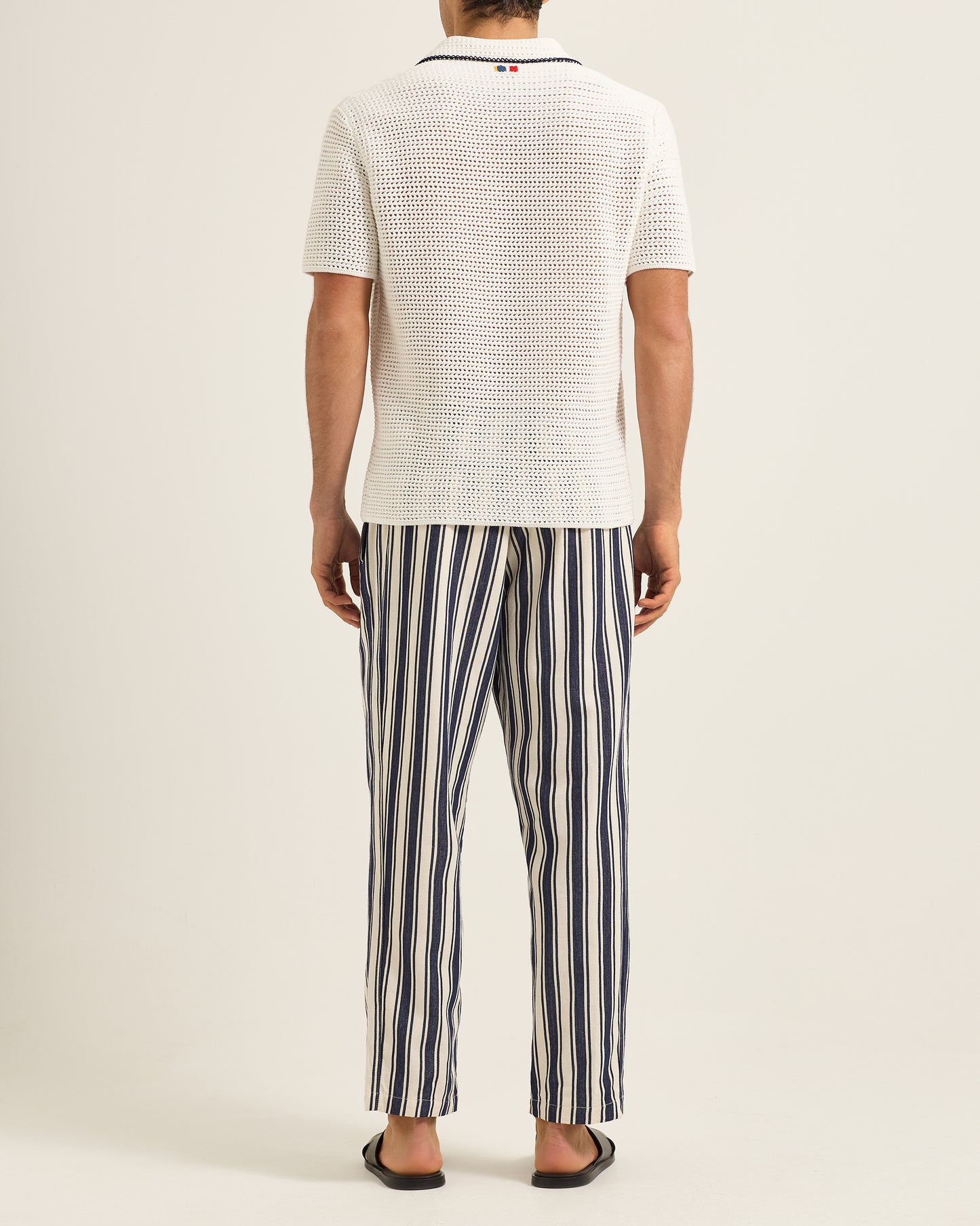 Person wearing a white textured shirt and striped pants on a plain background