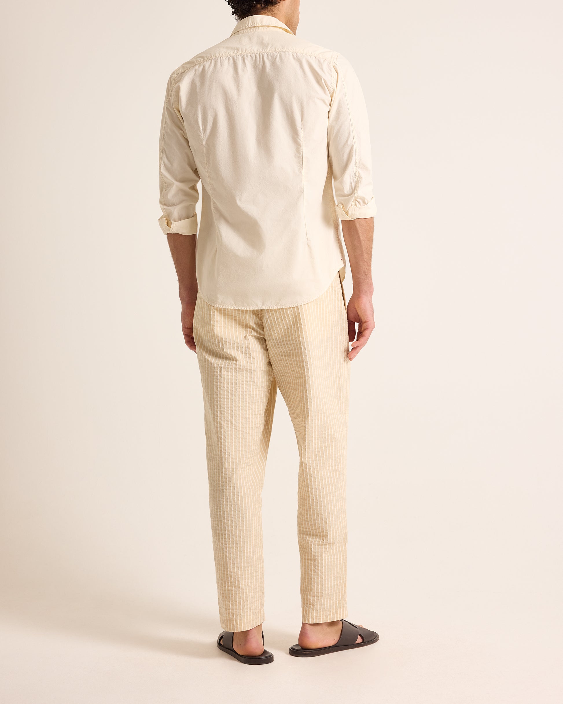 Man wearing light beige shirt and trousers with drawstring waist on a light background