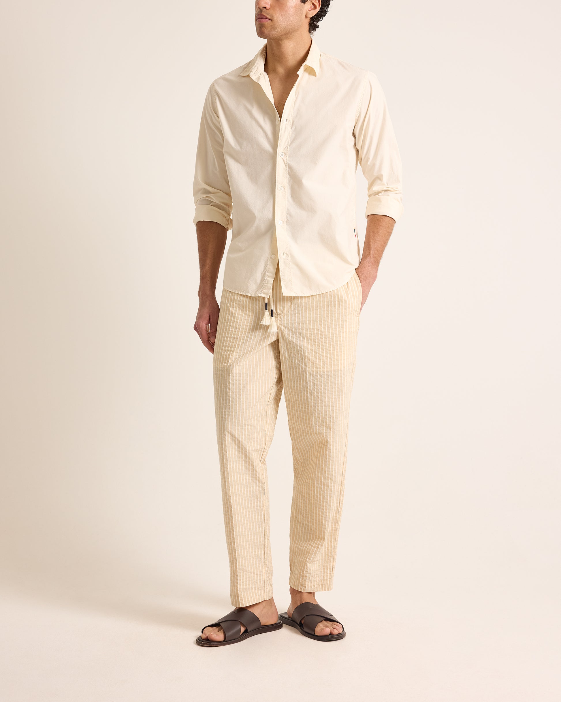 Man wearing light beige shirt and trousers with drawstring waist on a light background