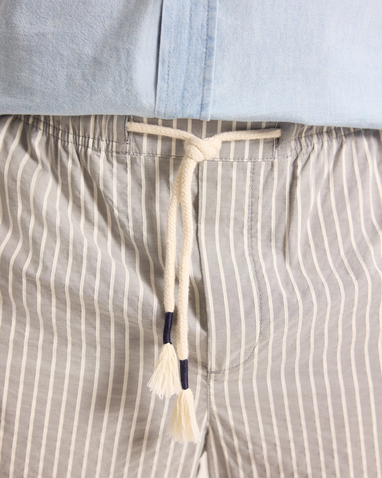Light grey trousers with light stripe and drawstring waist, worn with a light blue shirt