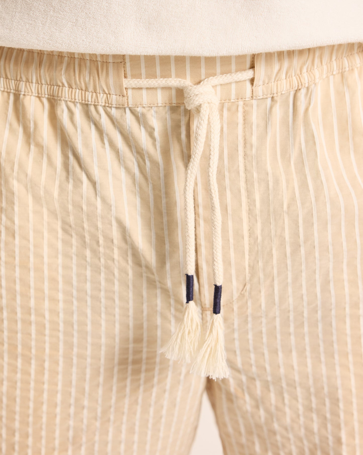 Light beige shorts with light stripe and drawstring waist, worn with a light t-shirt