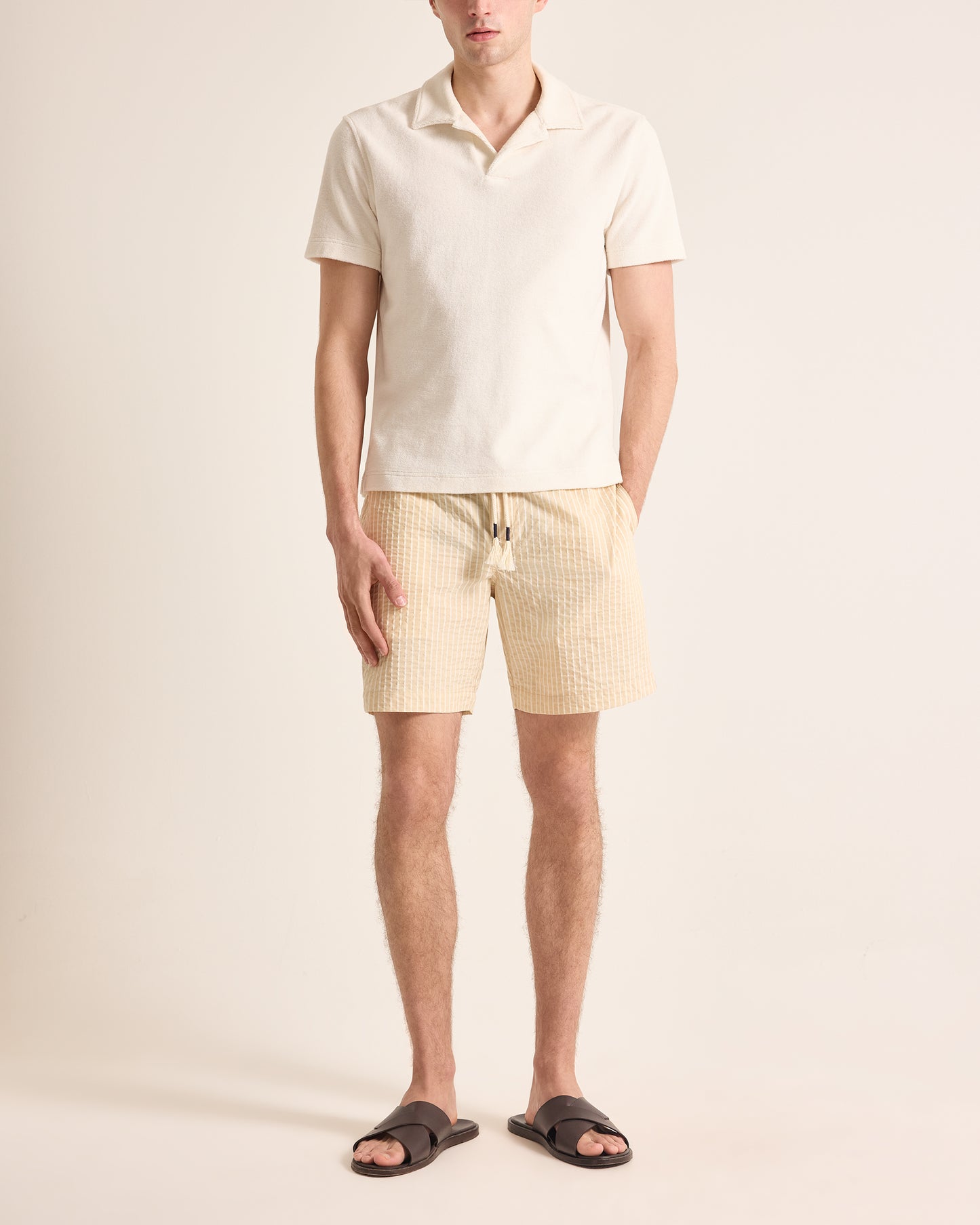 Man wearing a light-colored polo shirt and shorts on a plain background