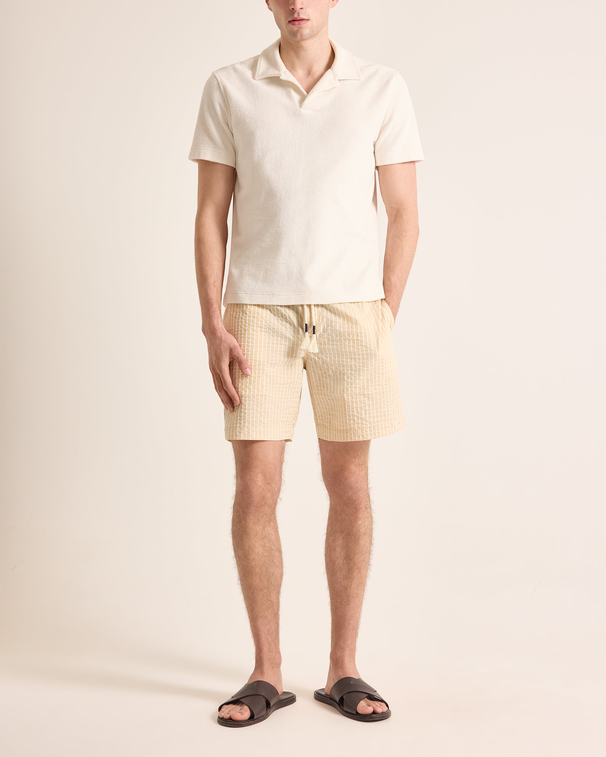 Man wearing a light-colored polo shirt and shorts on a plain background