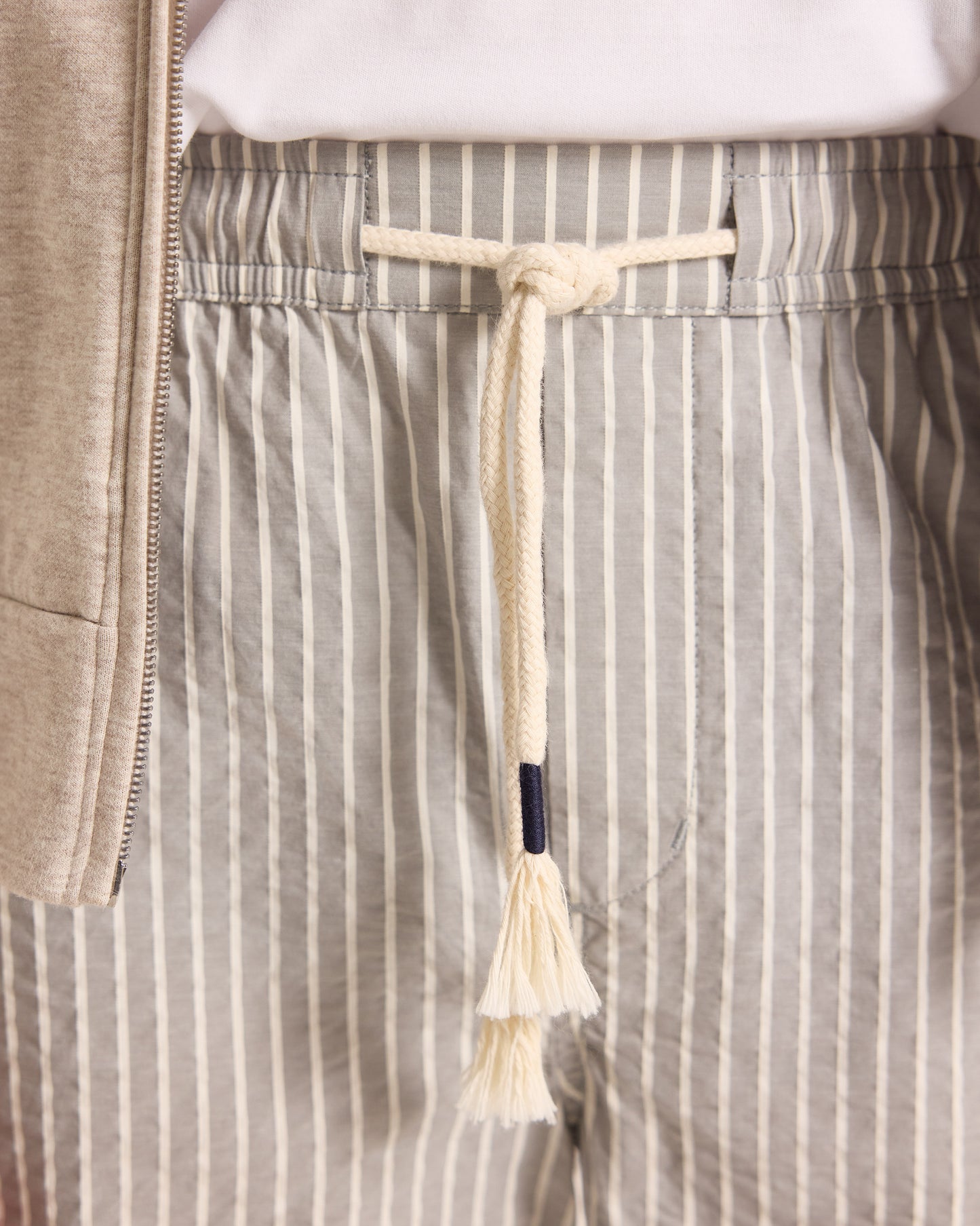 Close-up of striped pants with a drawstring and tassel detail.