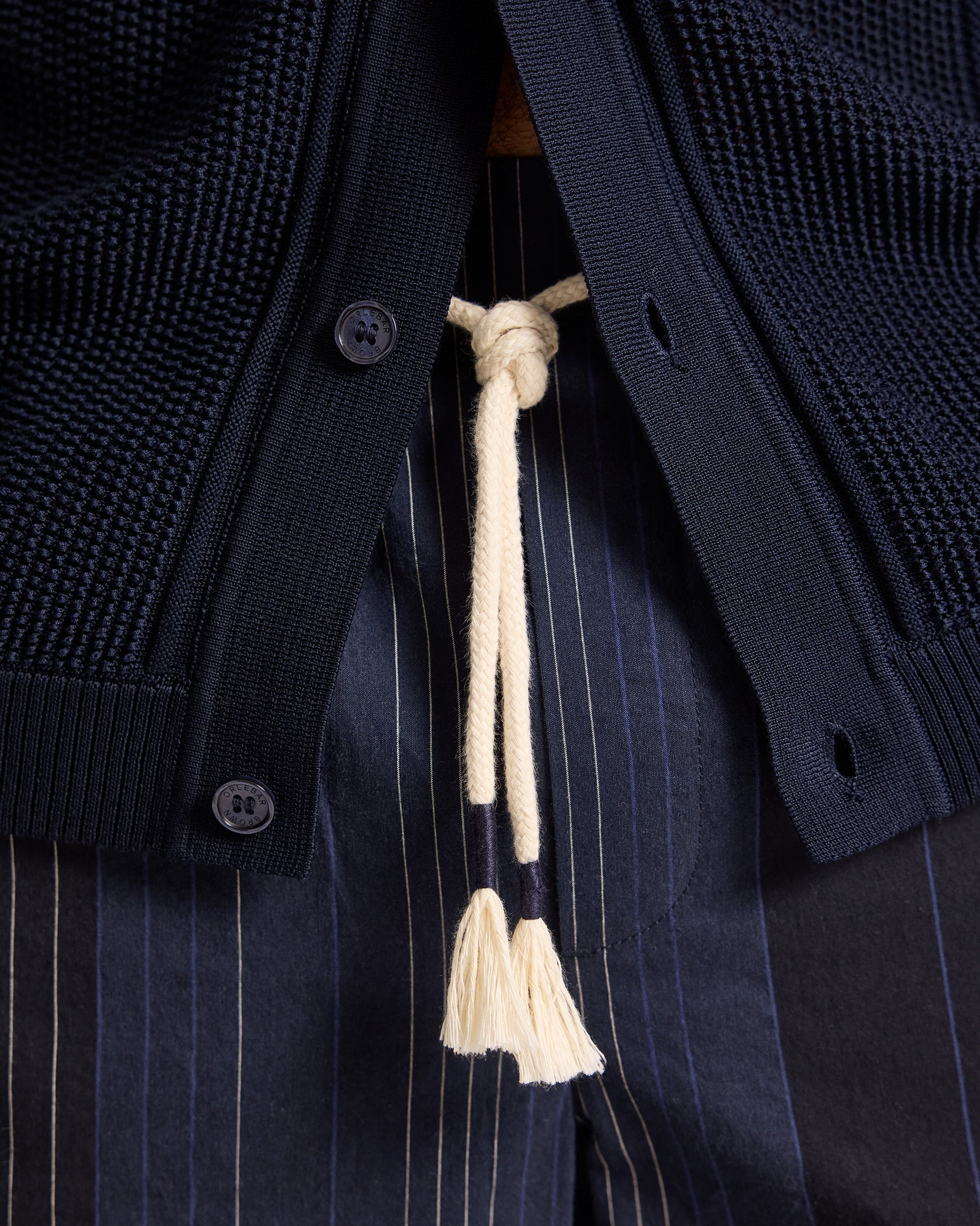 Navy cardigan with a tassel detail on a dark background