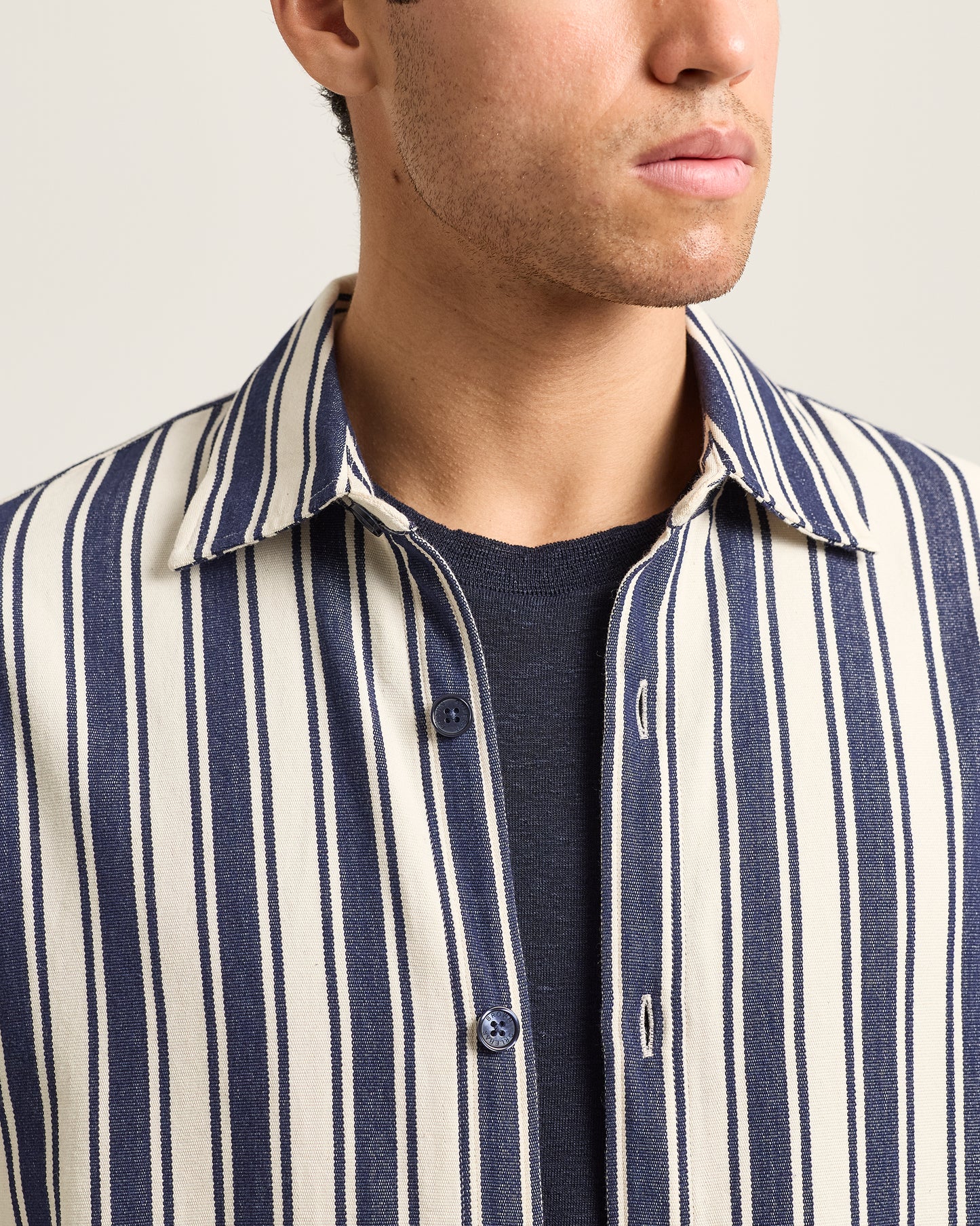 Close-up of a person wearing a navy and white striped shirt over a dark t-shirt.
