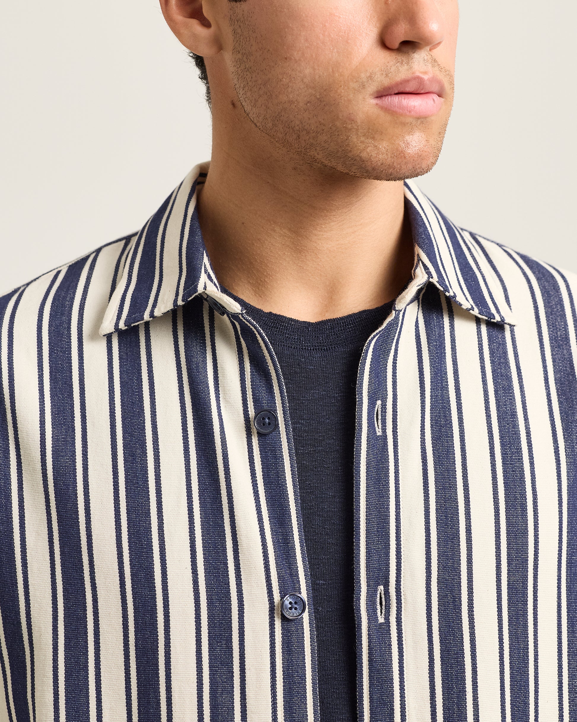 Close-up of a person wearing a navy and white striped shirt over a dark t-shirt.