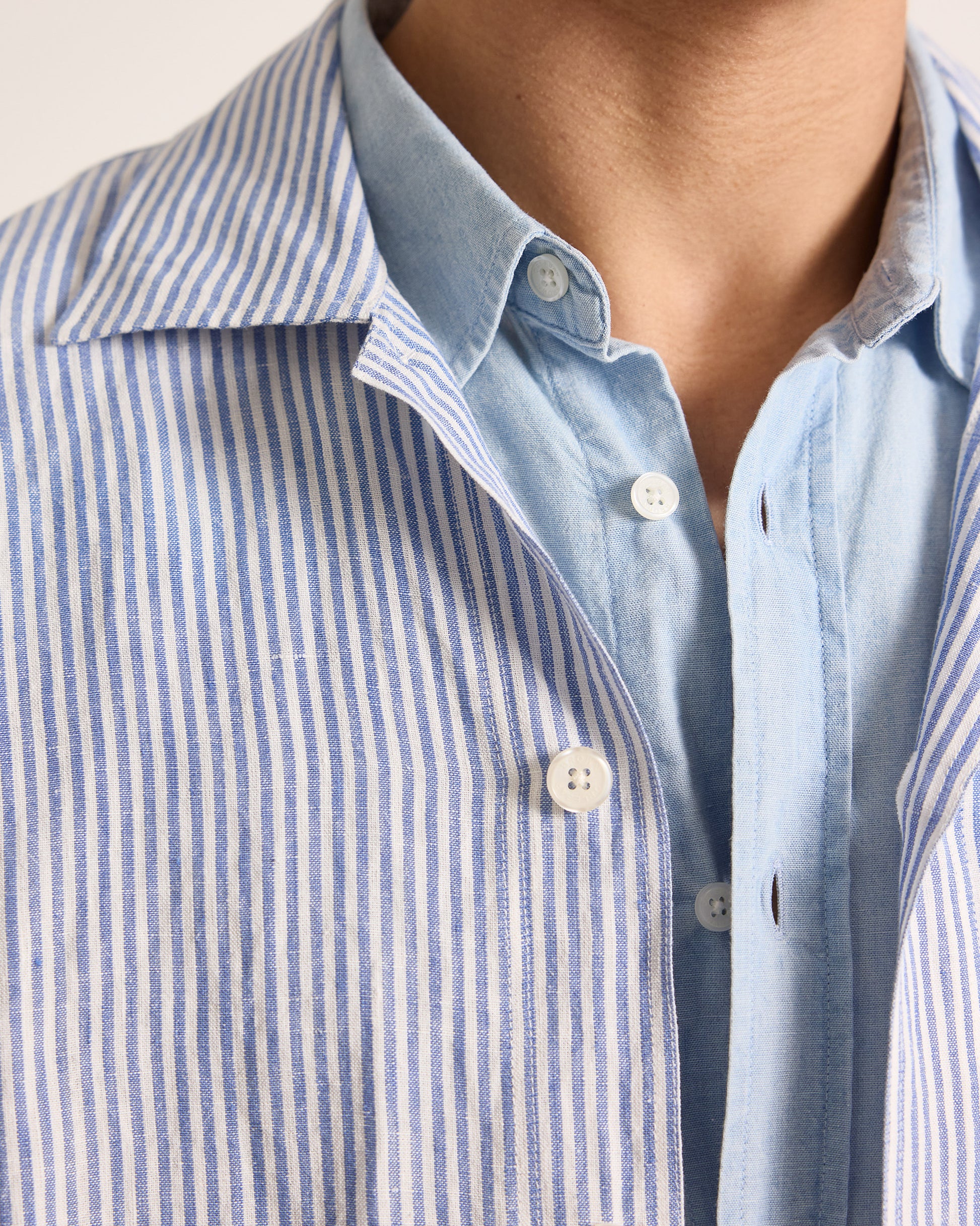 Close-up of a person wearing a blue and white striped shirt with a light blue collar.