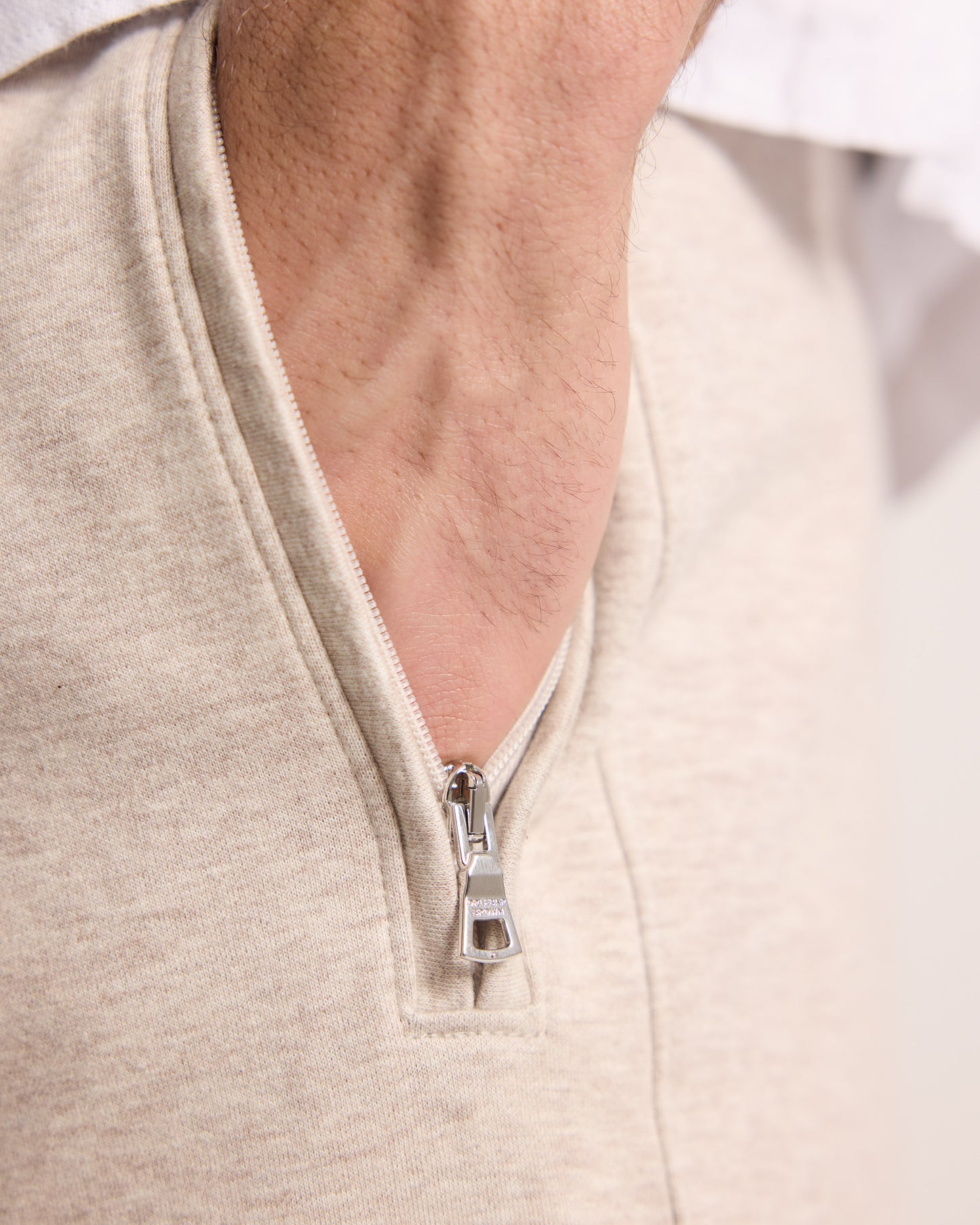 Close-up of a beige cashmere sweatpants with a zipper on a neutral background