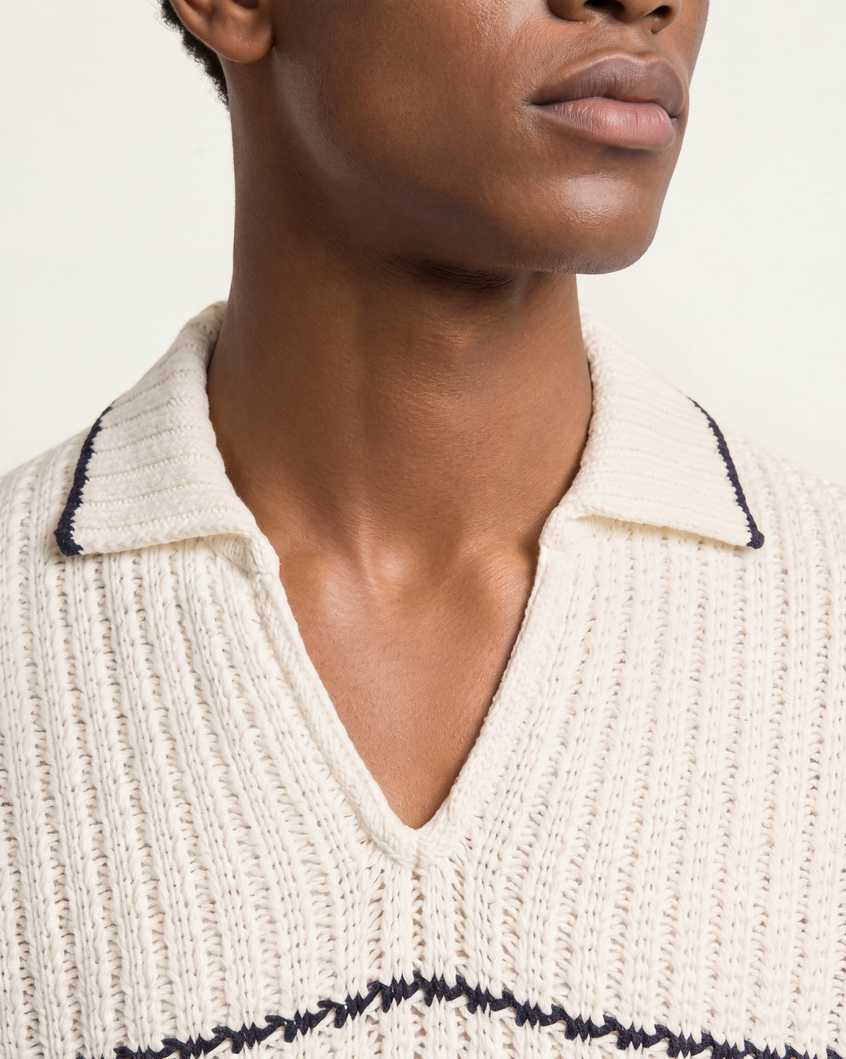 Closeup of white knitted polo shirt with black tipping detail on collar