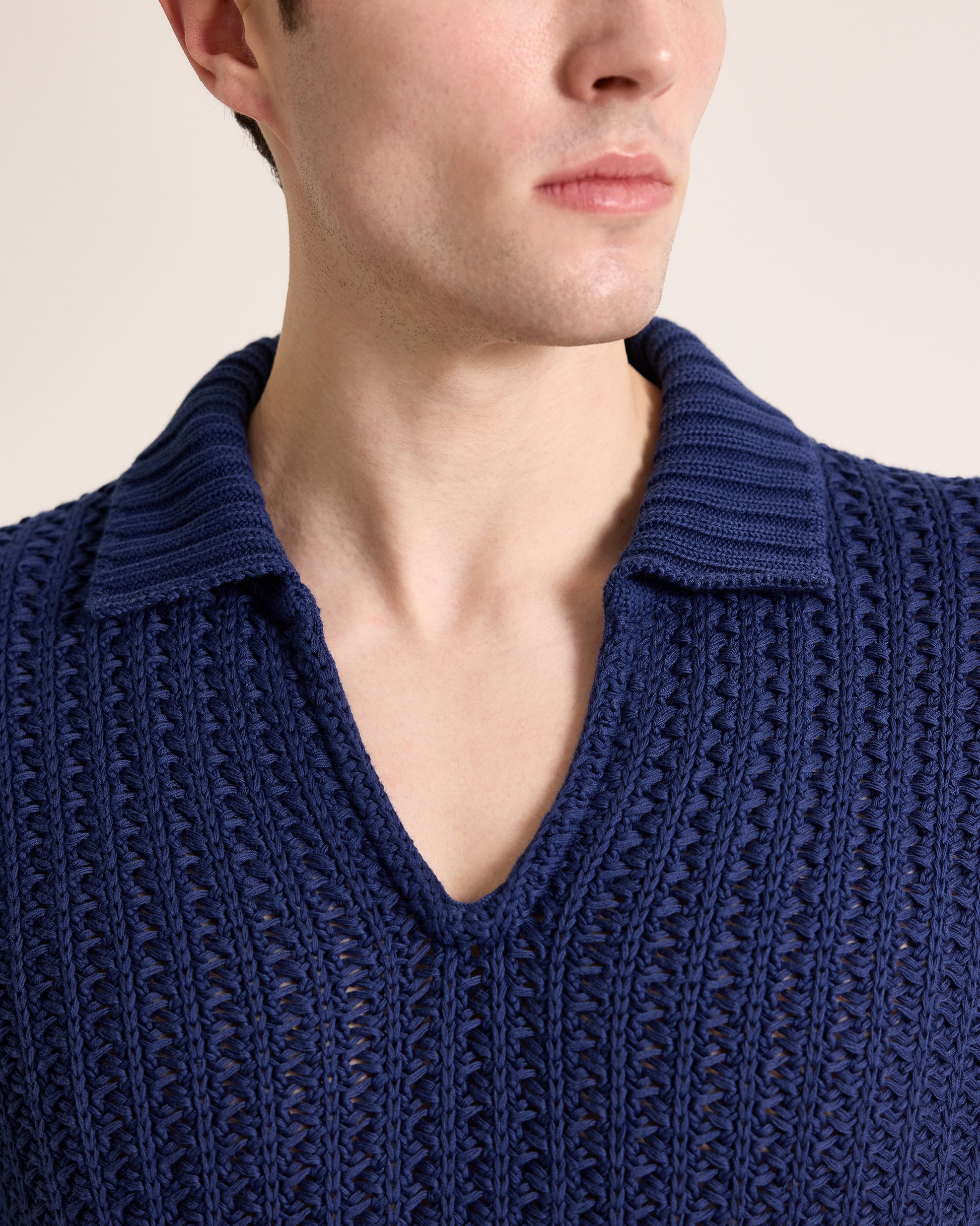 Close-up of a person wearing a blue knitted sweater with a plain background
