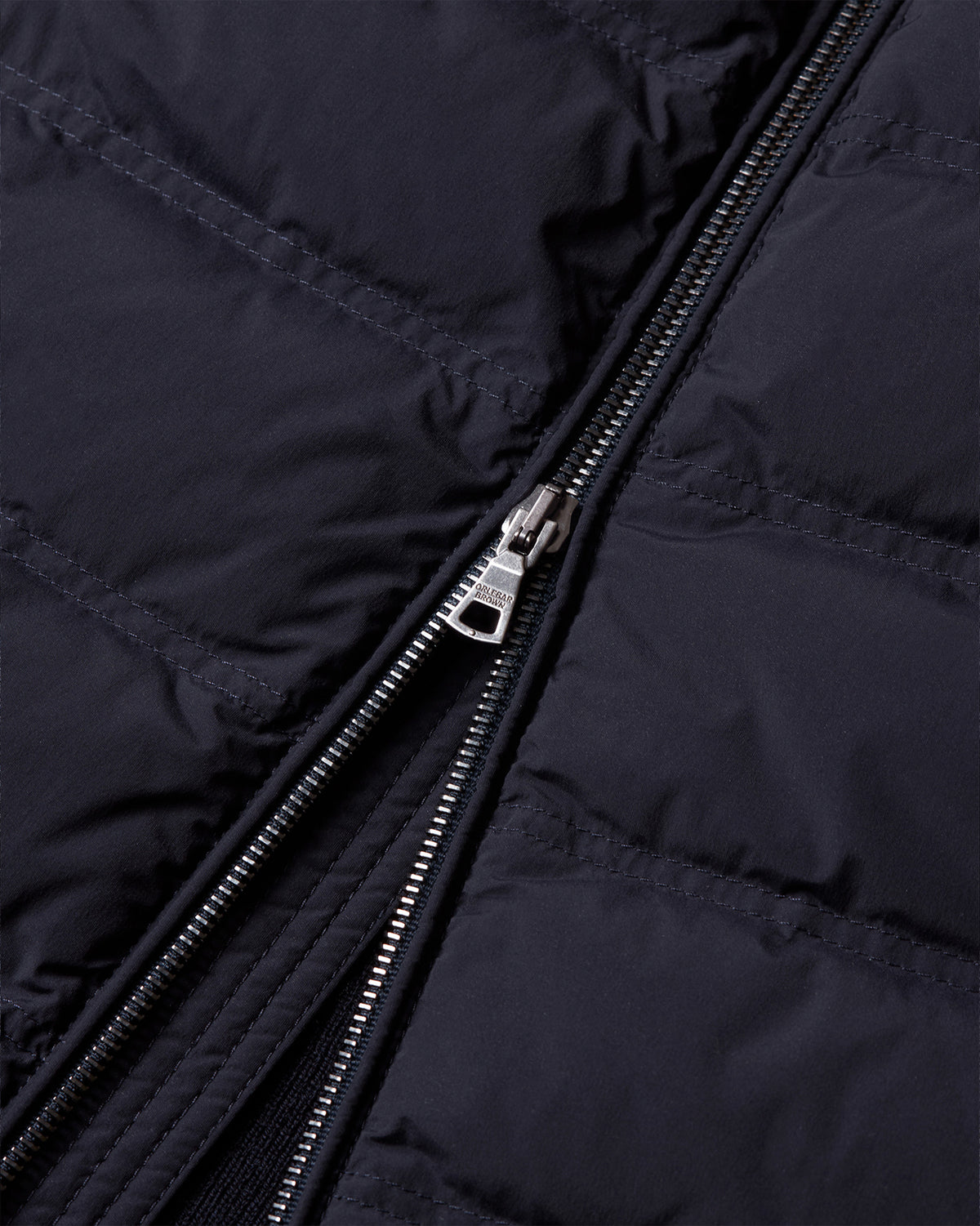 Close-up of a dark navy puffer jacket showing the quilted stitching and a silver metal zipper.