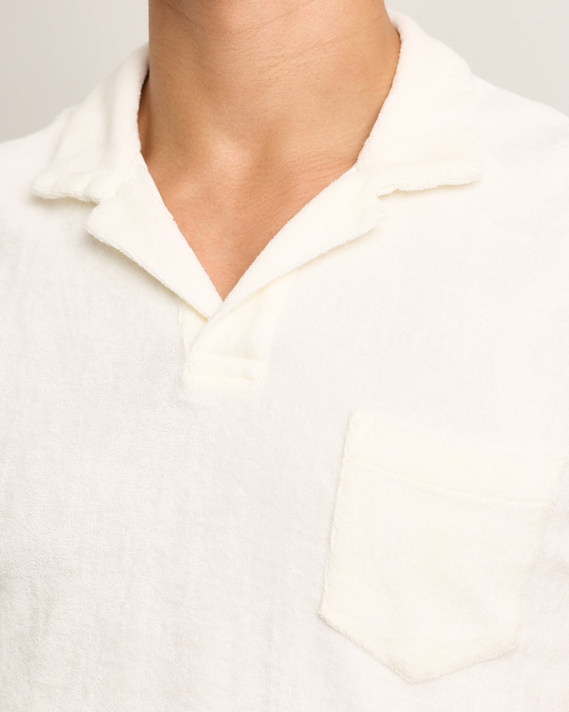 Close-up of a person wearing a white towelling polo shirt with a collar.
