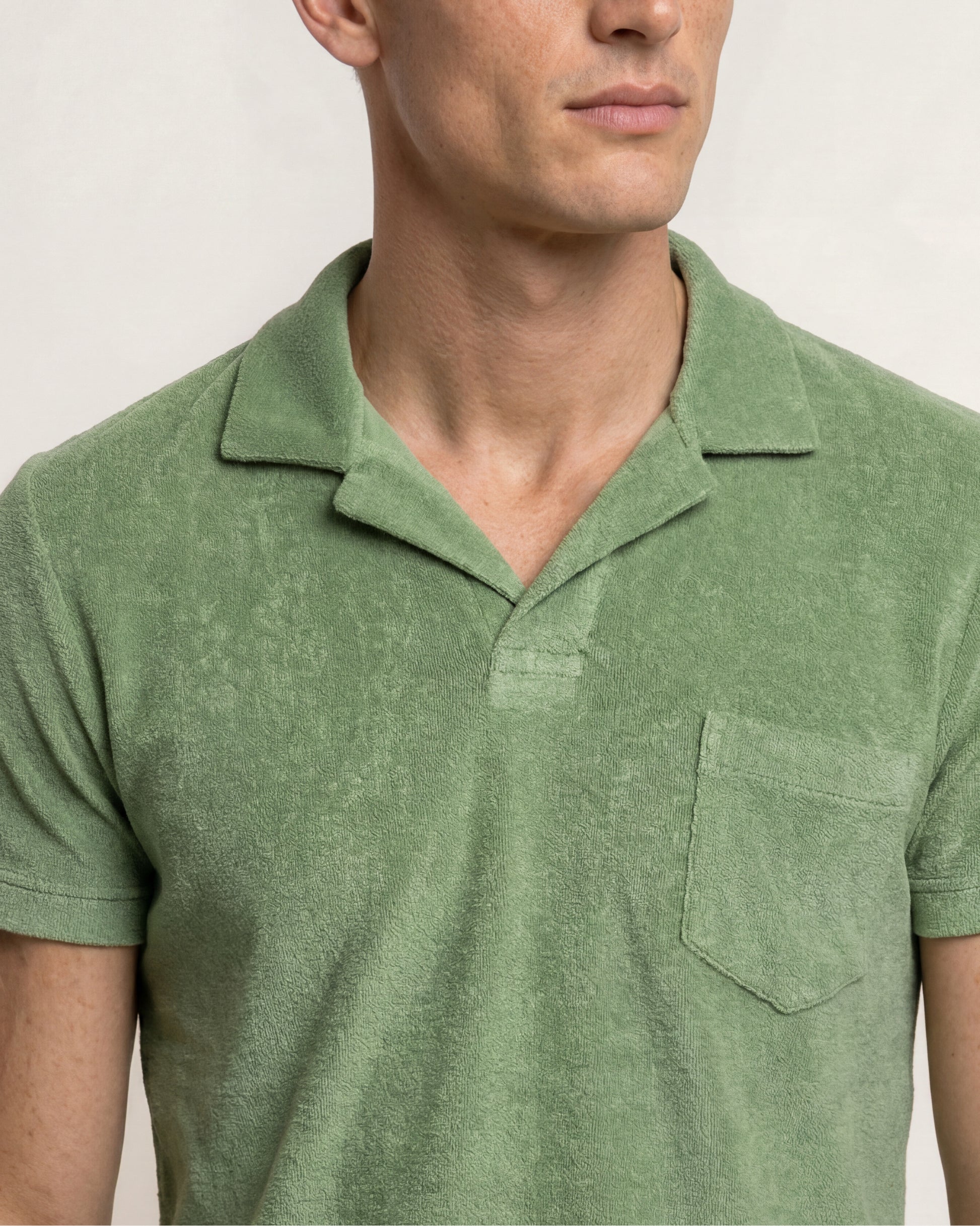 Man wearing a green polo shirt against a plain background