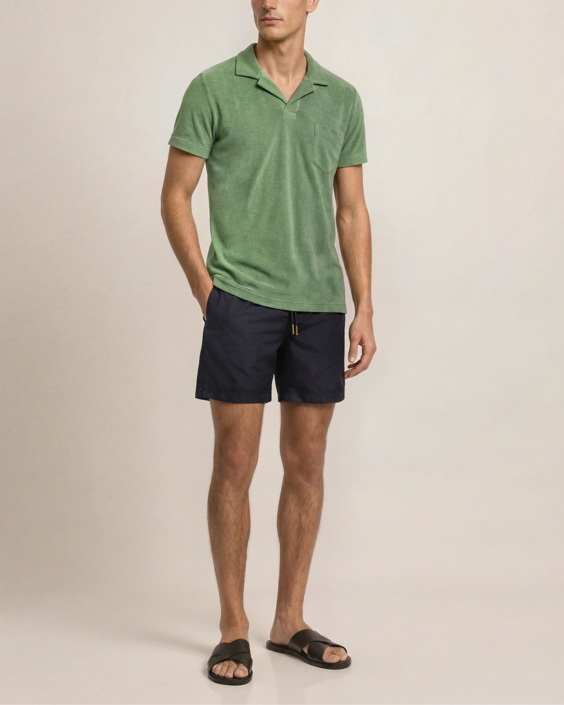 Man wearing a green polo shirt and black shorts on a beige background